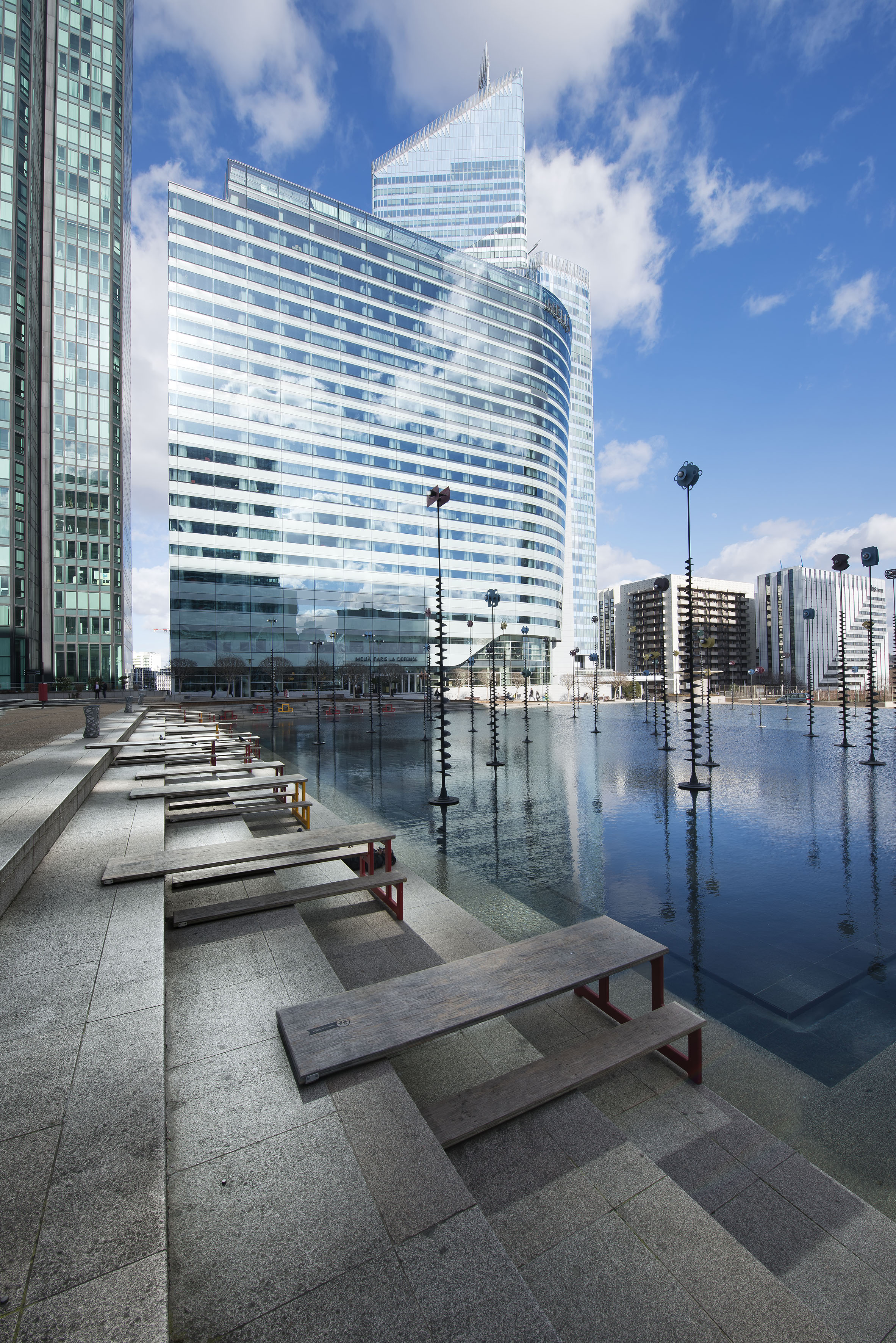 a water with benches and a large building in the background