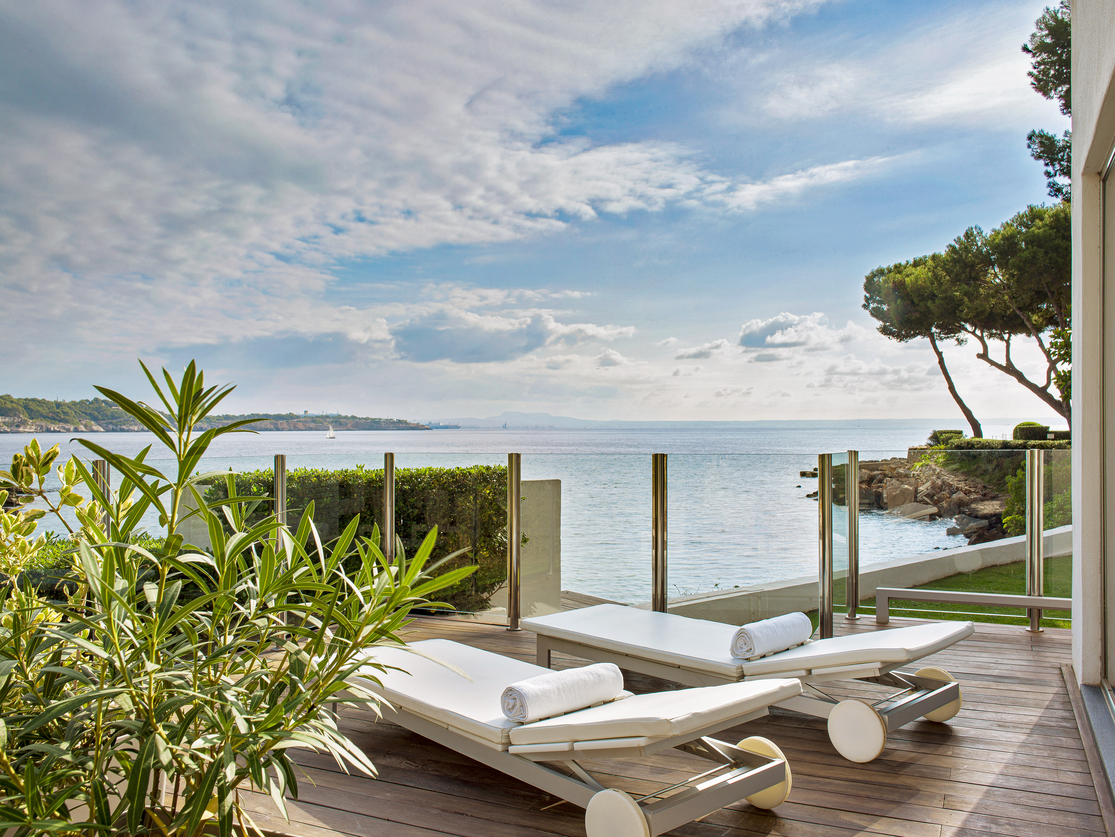 Luxury ocean view patio with two white lounge chairs on a wooden deck.