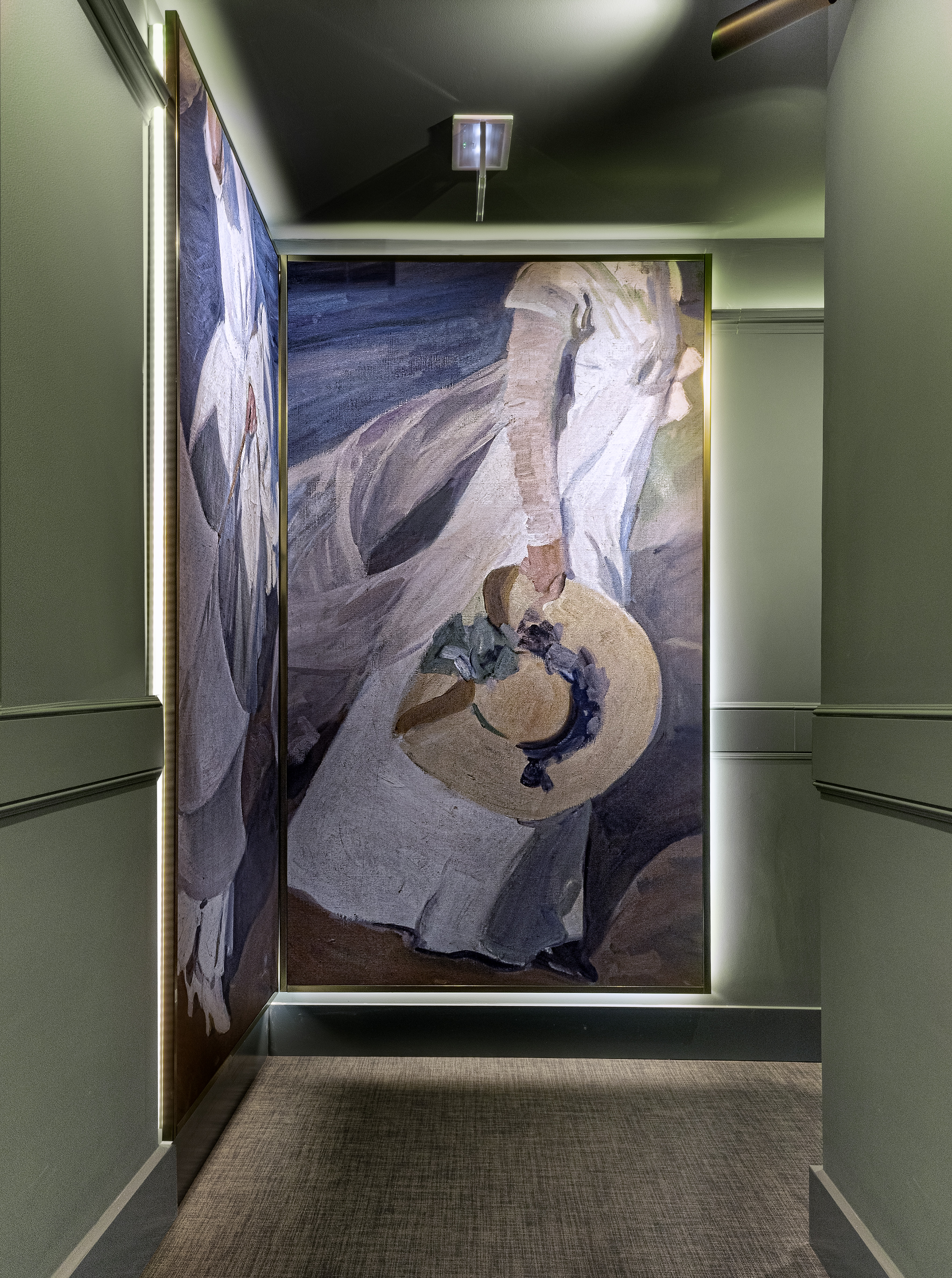 Modern hotel corridor with large art of a woman holding a hat, LED lighting.
