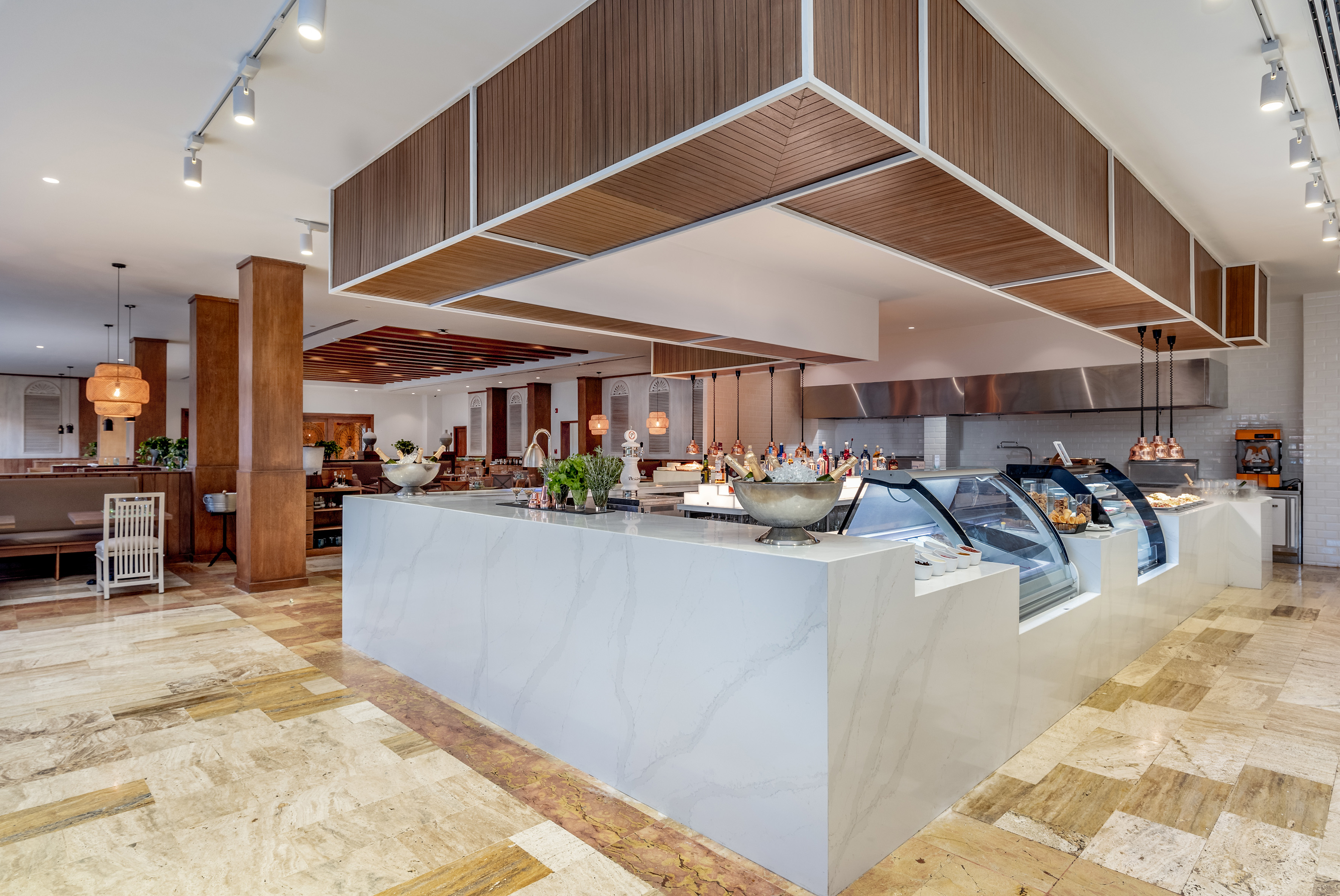 Modern restaurant buffet with marble counter, food displays, and wood paneling.