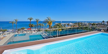 ein Pool mit Palmen und Strand im Hintergrund