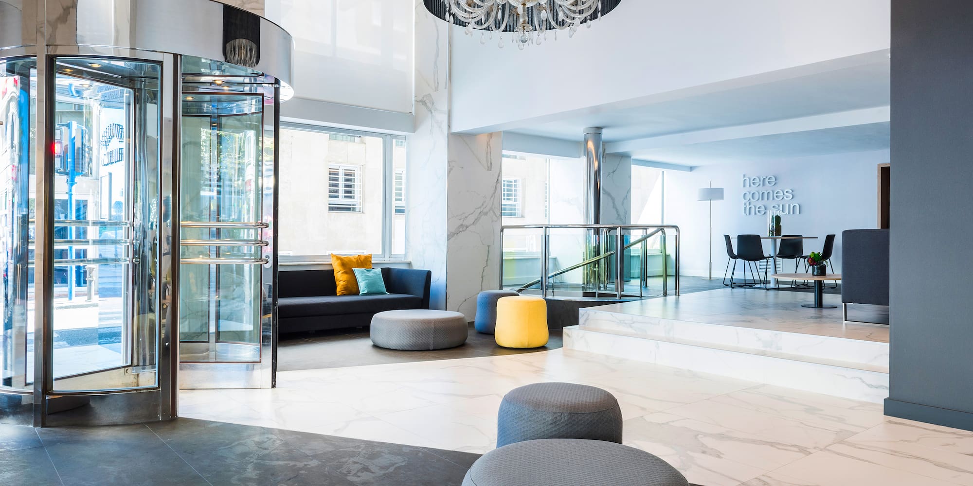 a room with a glass elevator and a round chandelier