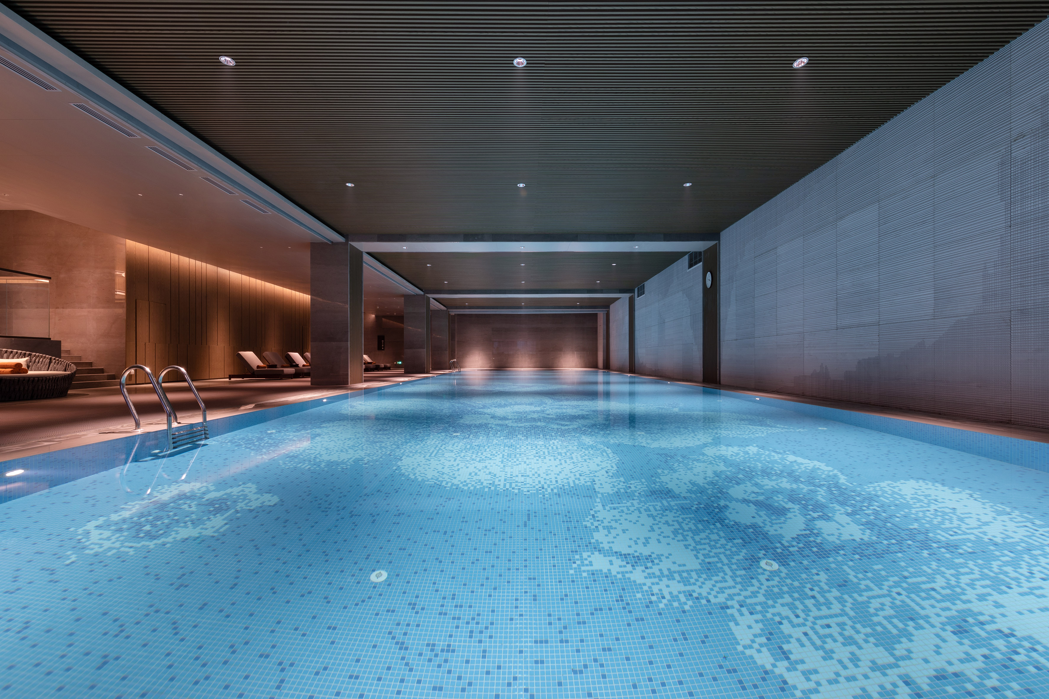 Luxury indoor lap pool with modern design, mosaic tiles, and ambient lighting.