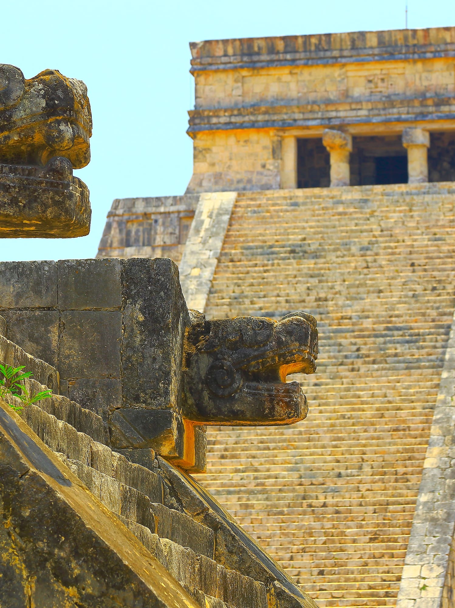 Chichen Itza Mayan pyramid with stone Kukulkan serpent heads on staircase.