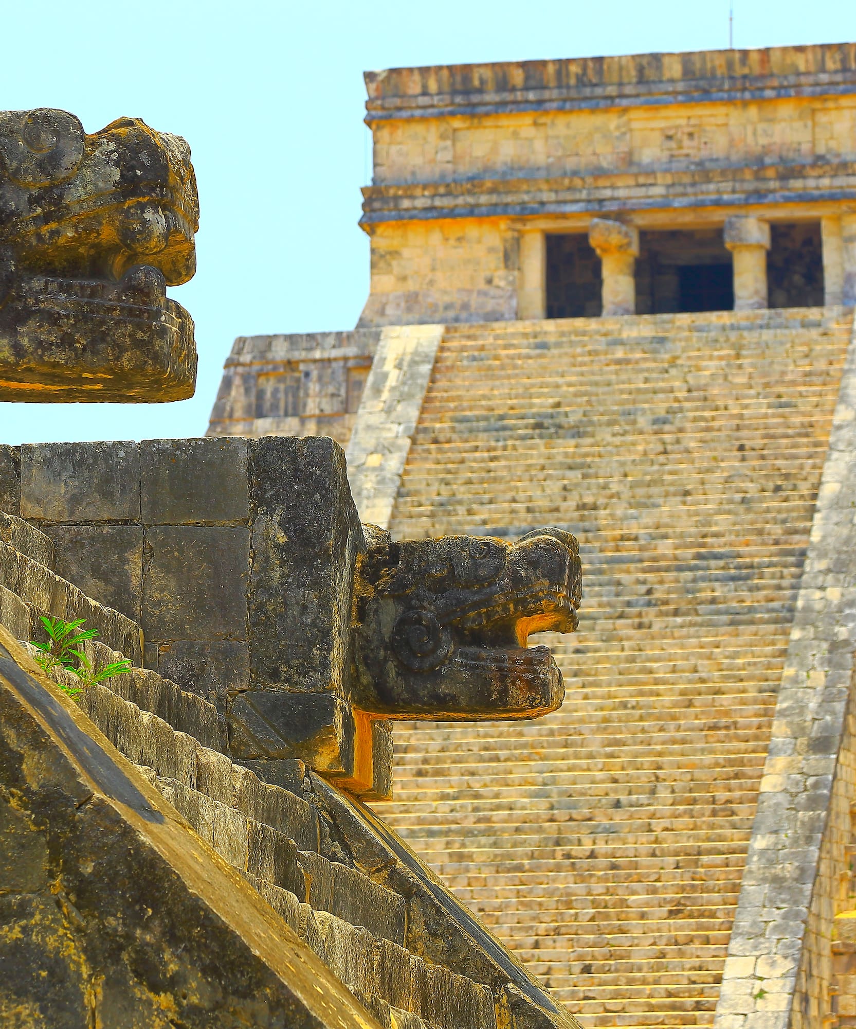 Chichen Itza Mayan pyramid with stone Kukulkan serpent heads on staircase.