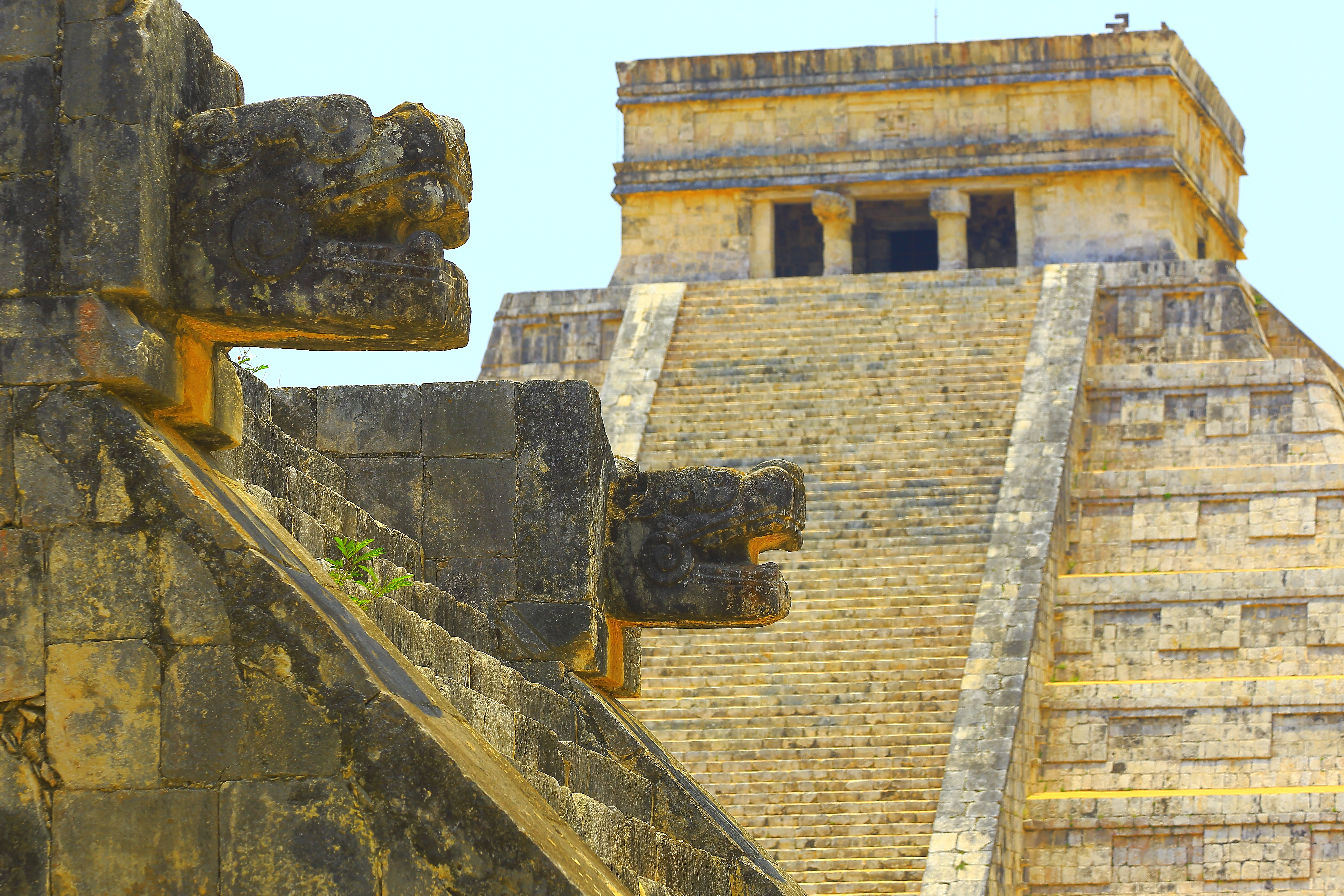 Chichen Itza Mayan pyramid with stone Kukulkan serpent heads on staircase.