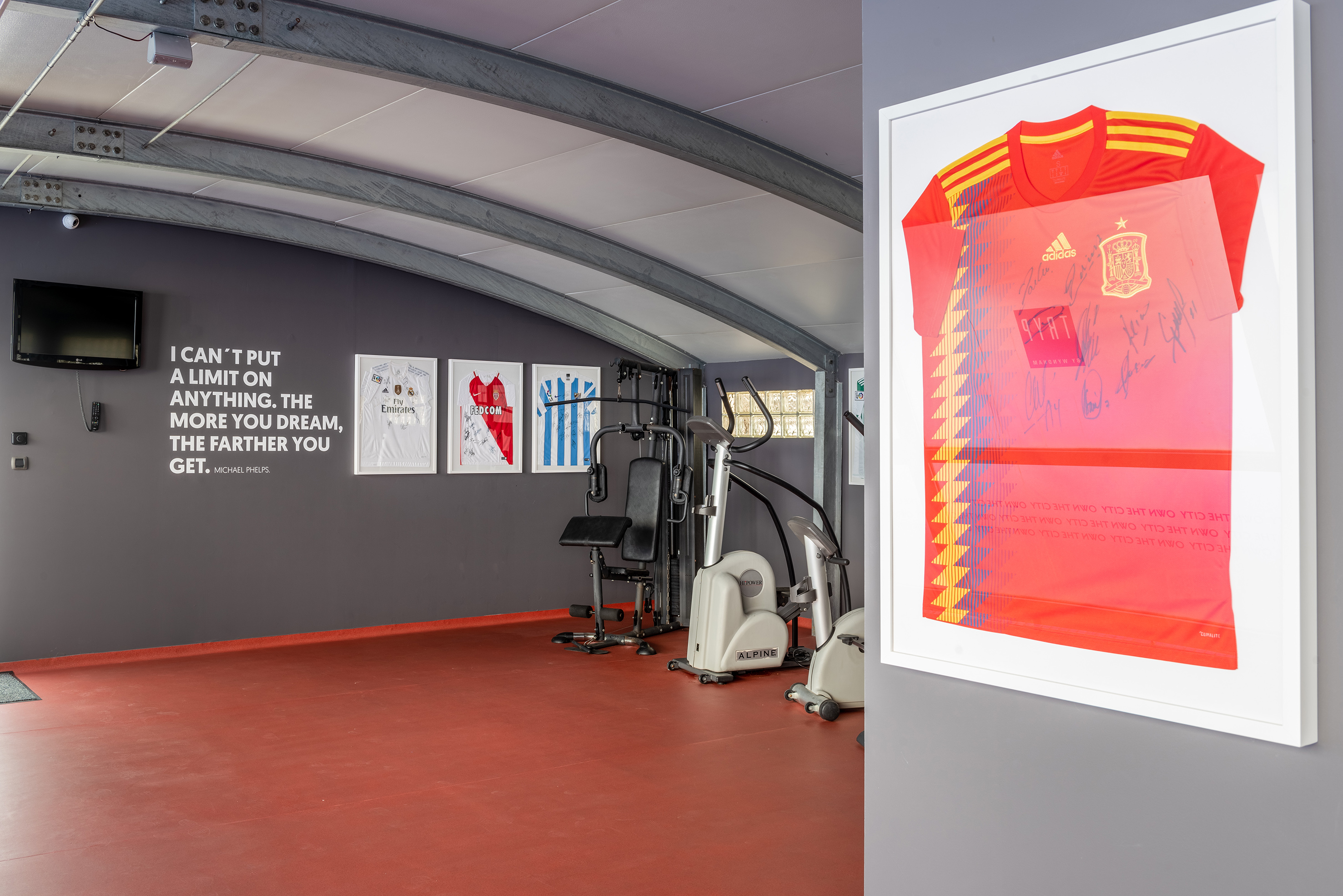 Home gym with signed sports jerseys, workout equipment, and motivational quote.