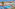 Aerial view of a tropical resort with a large swimming pool, palm trees, and white bungalows.