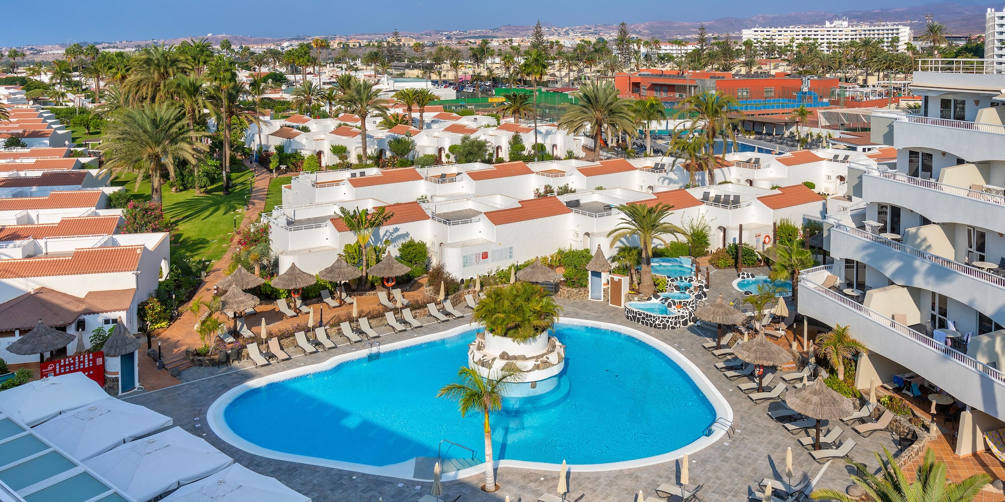 a pool and buildings with palm trees