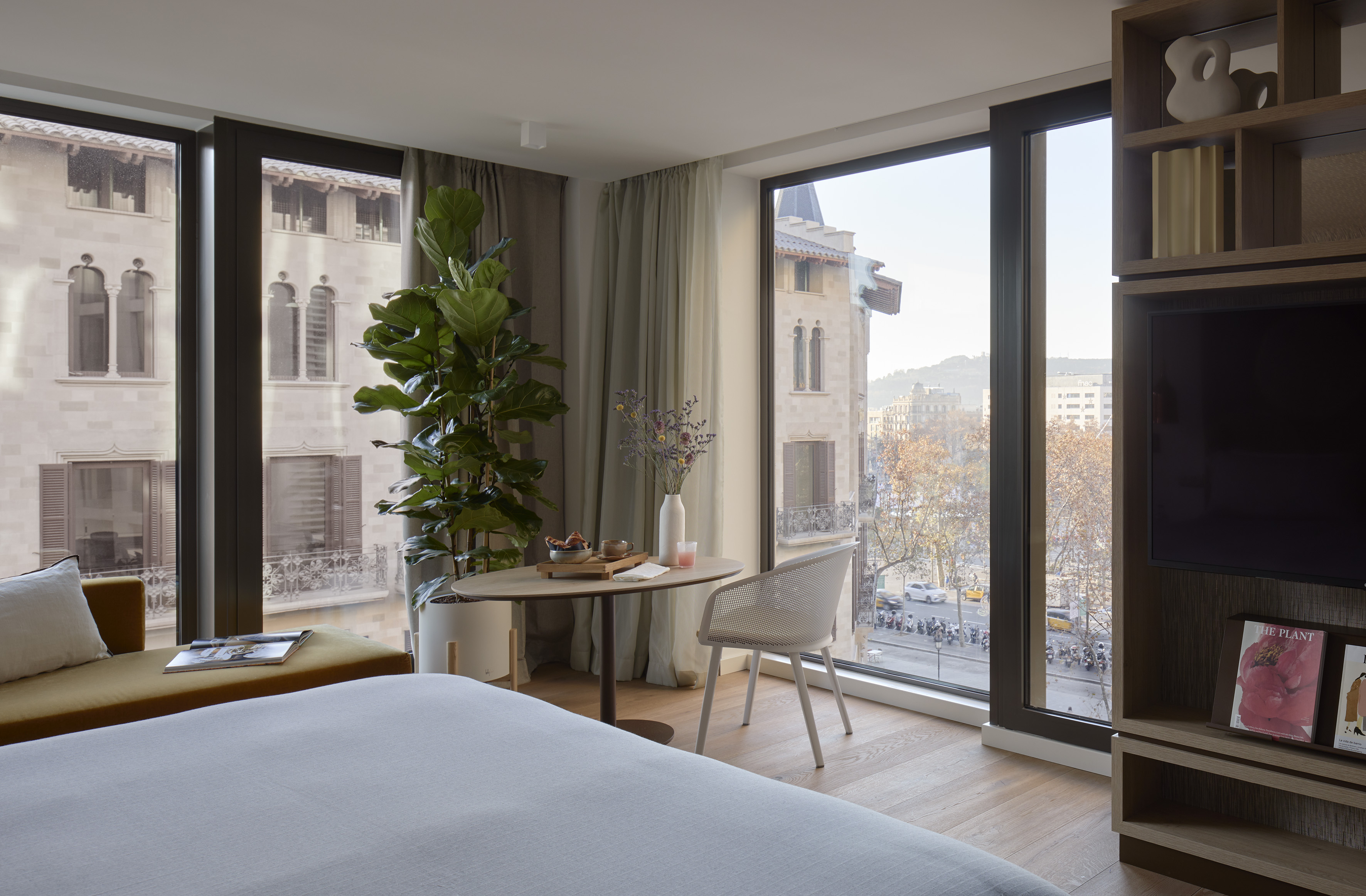 Contemporary hotel room with cityscape views, king bed, and dining area.