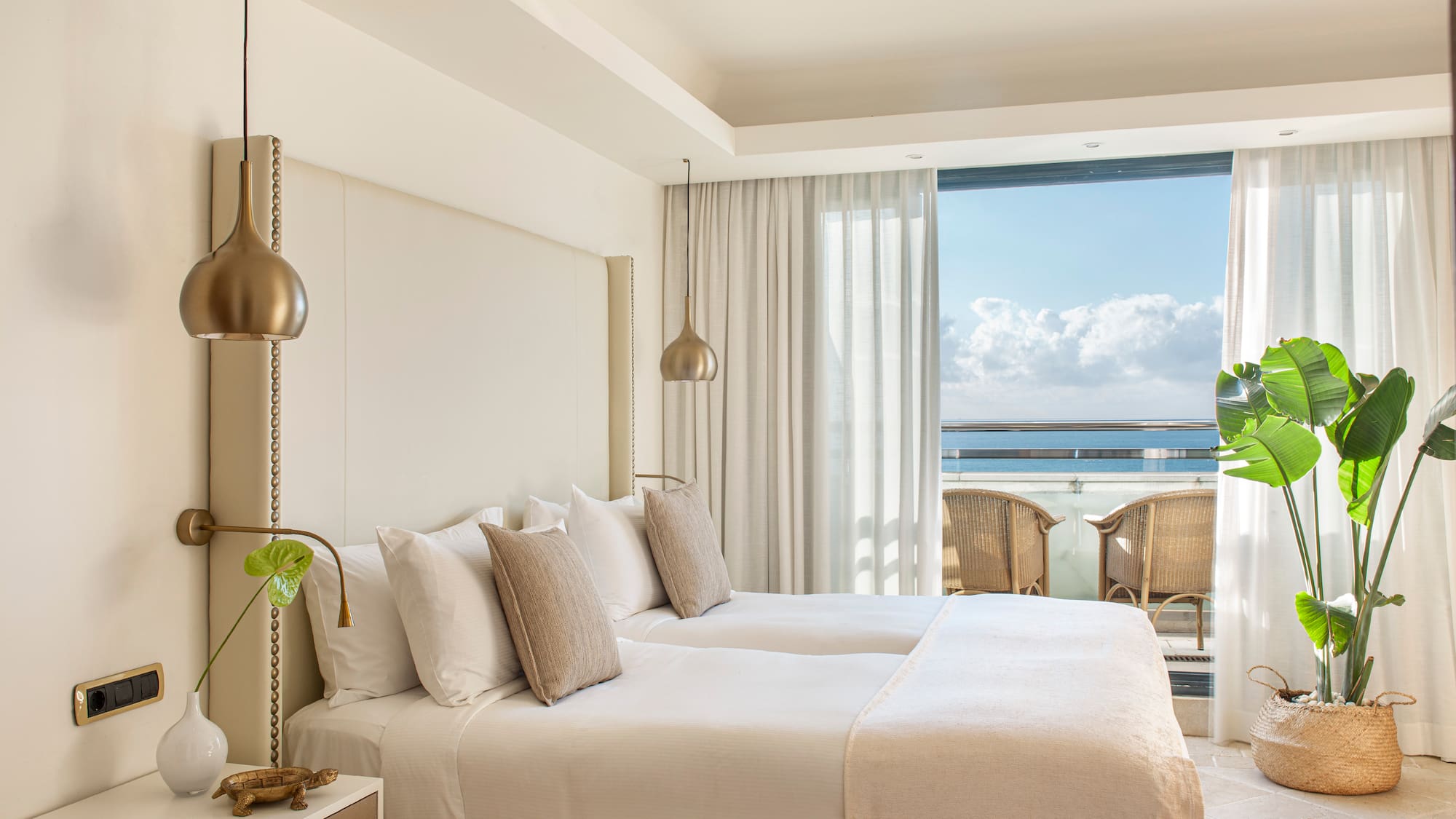 a bedroom with a large bed and a balcony overlooking the ocean