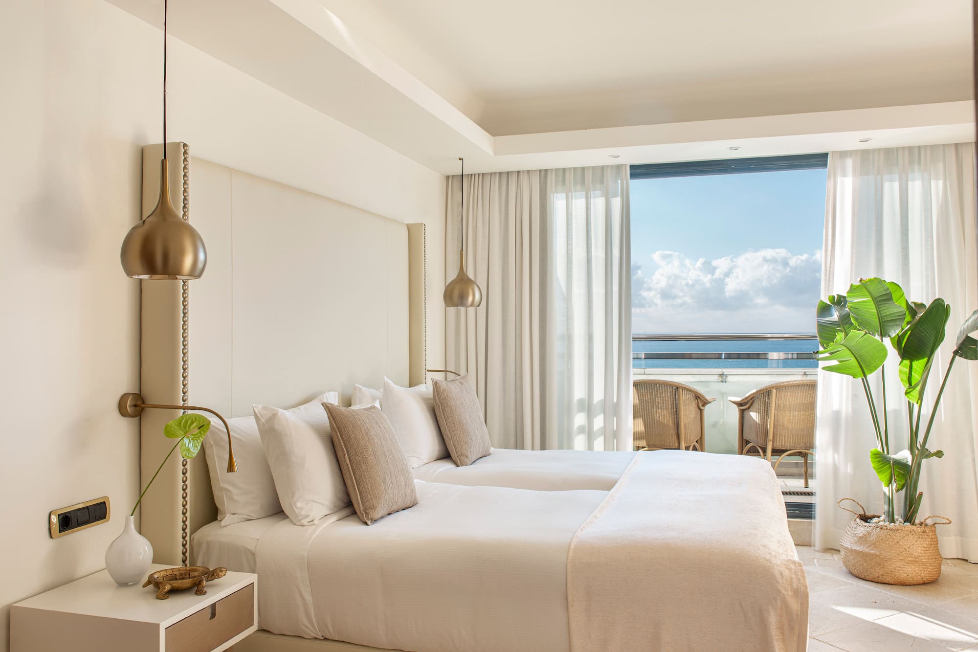 a bedroom with a large bed and a balcony overlooking the ocean