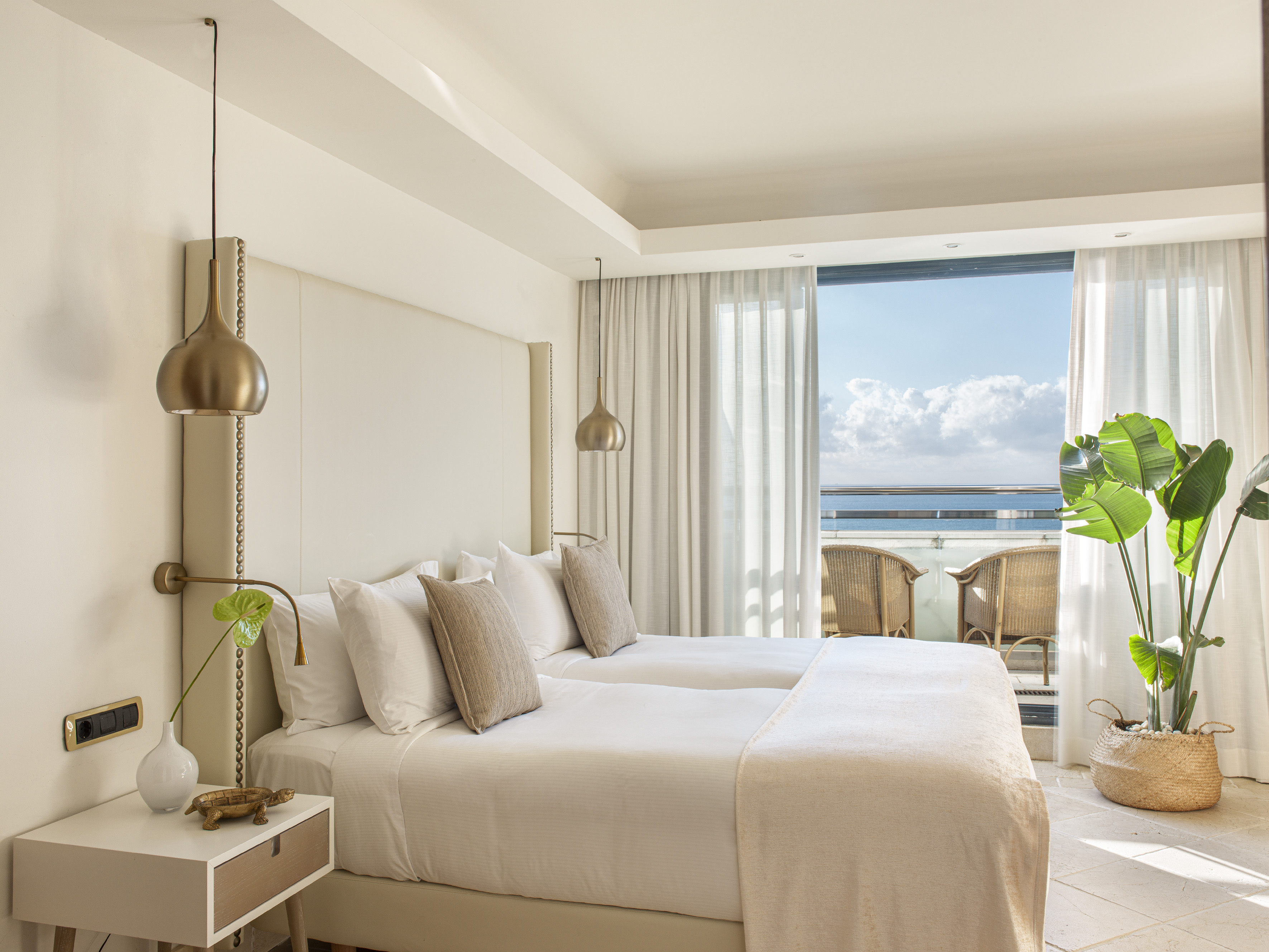 a bedroom with a large bed and a balcony overlooking the ocean