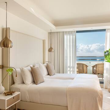 a bedroom with a large bed and a balcony overlooking the ocean