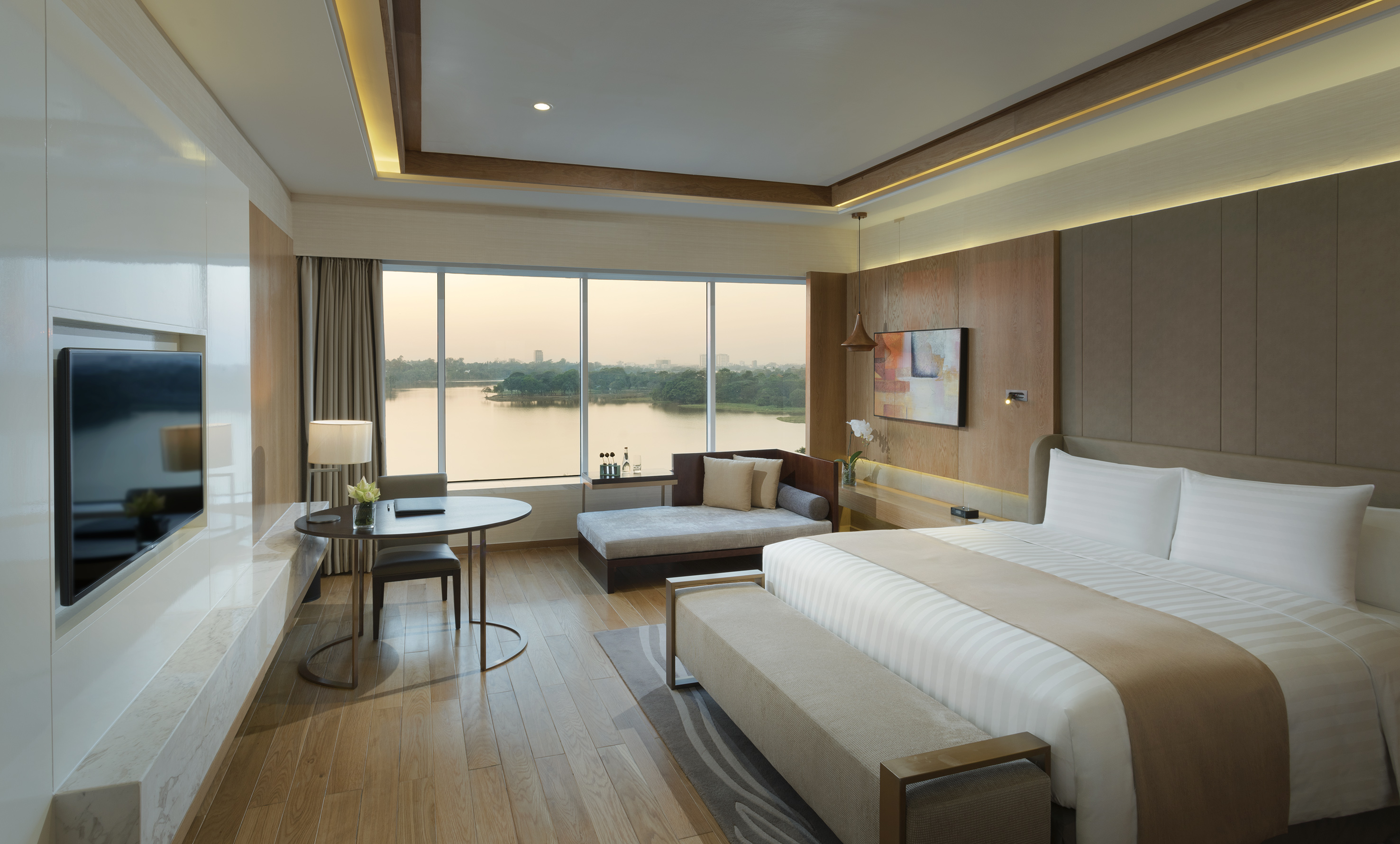 Elegant hotel suite overlooking a lake, featuring a king bed and modern decor.