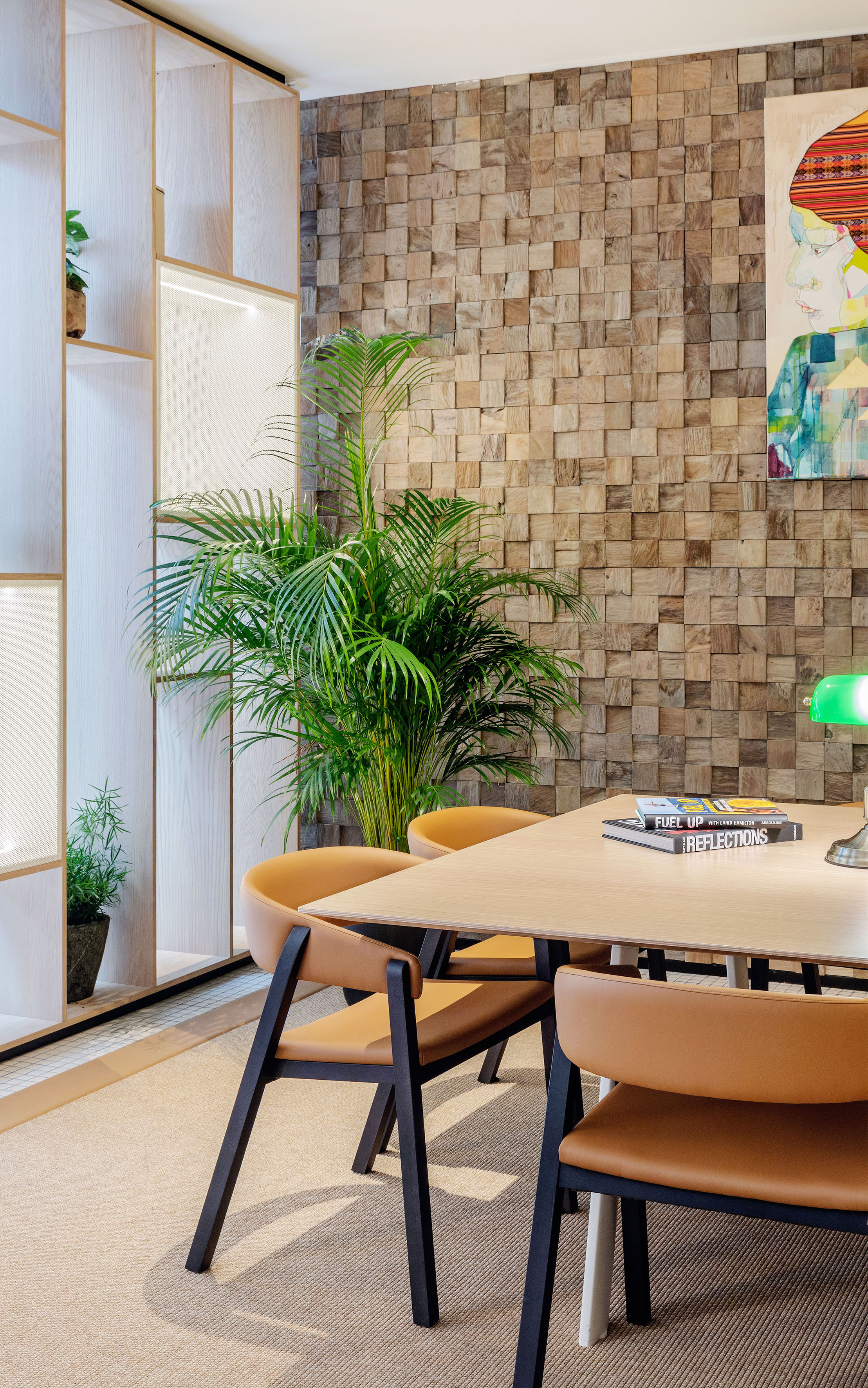 Modern meeting room with wood block accent wall, tan chairs, and green plant.