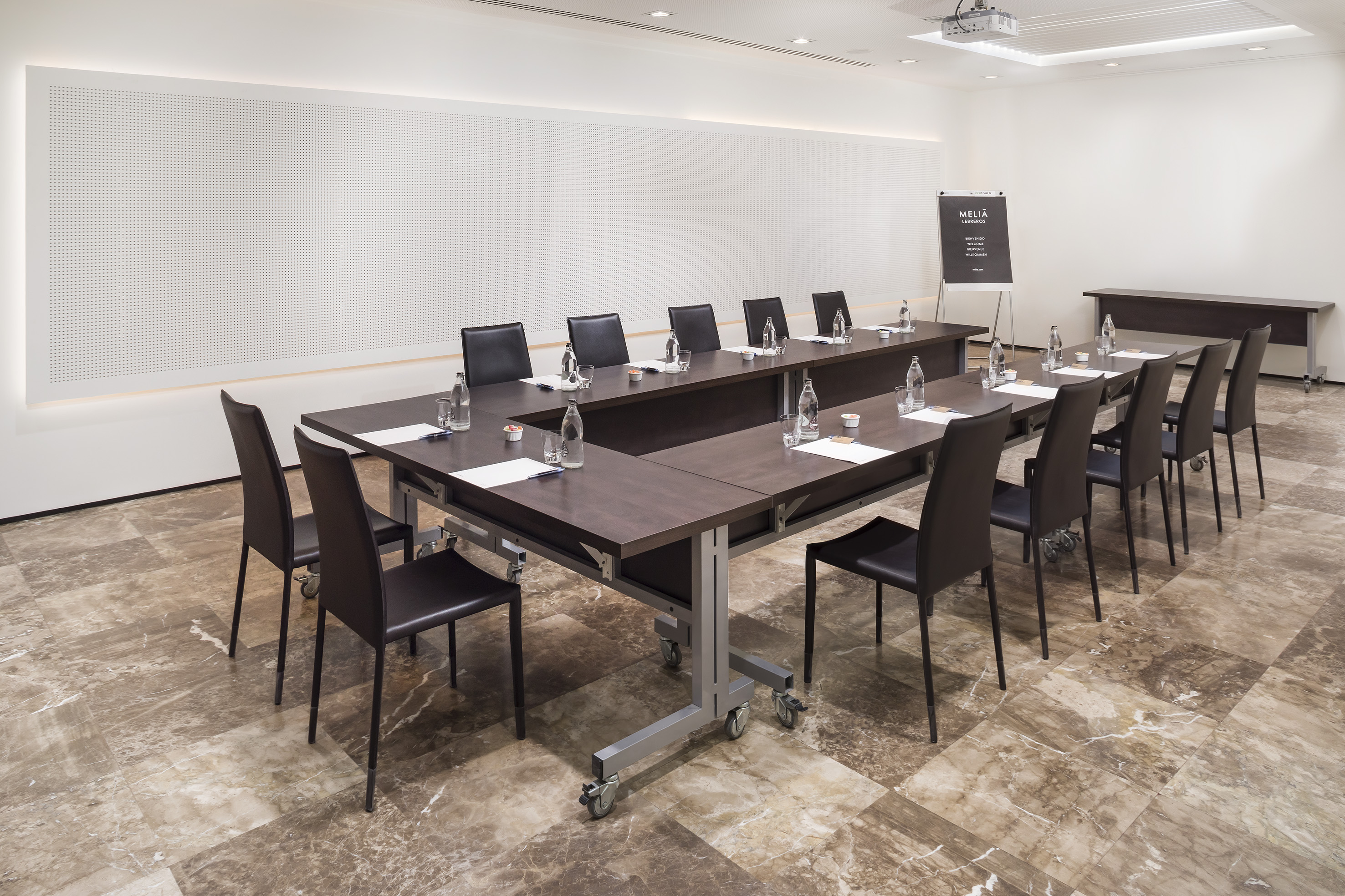 Meliá hotel conference room with U-shaped table, chairs, and projector.