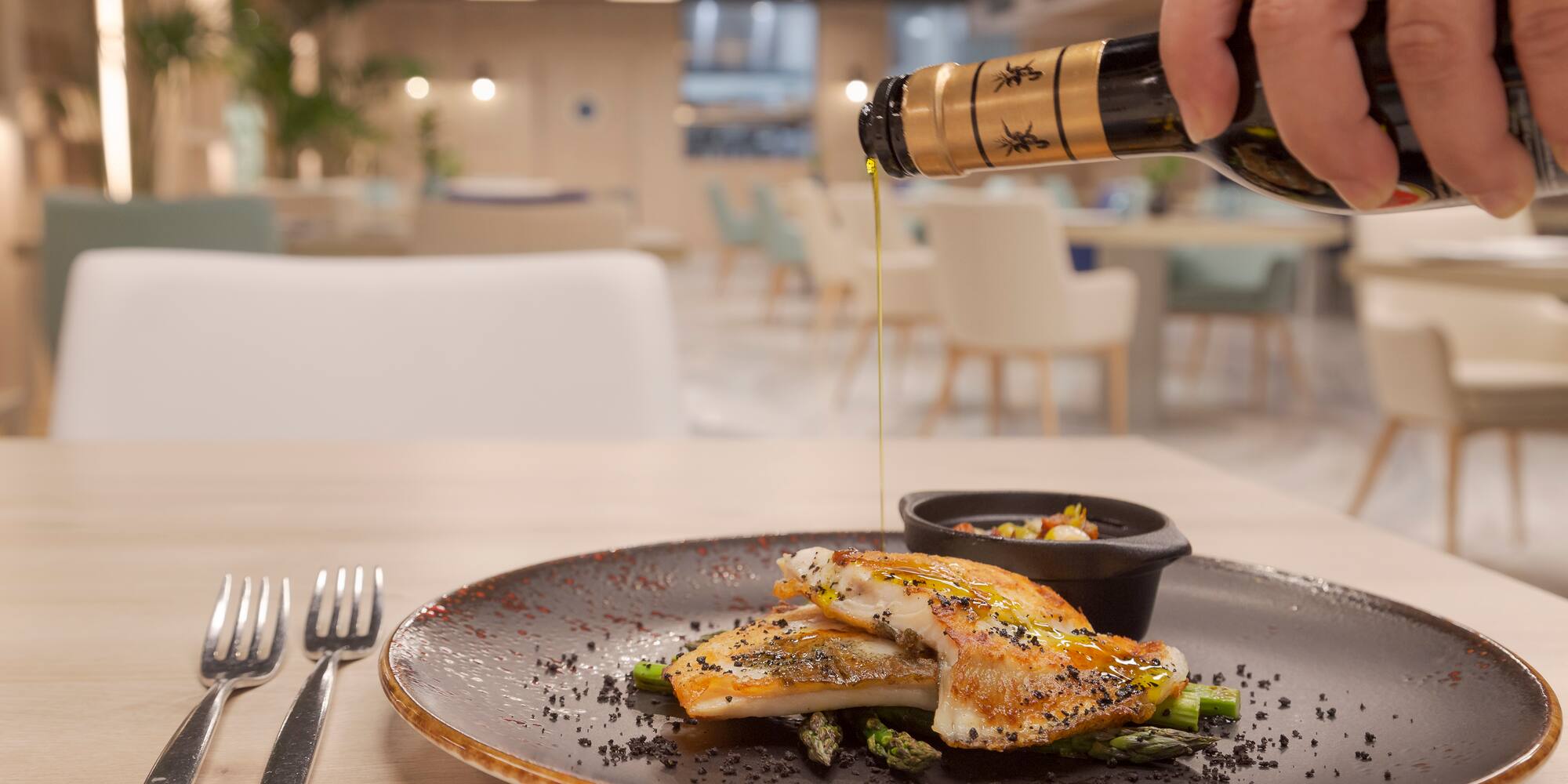 a person pouring a bottle of oil onto a plate of food