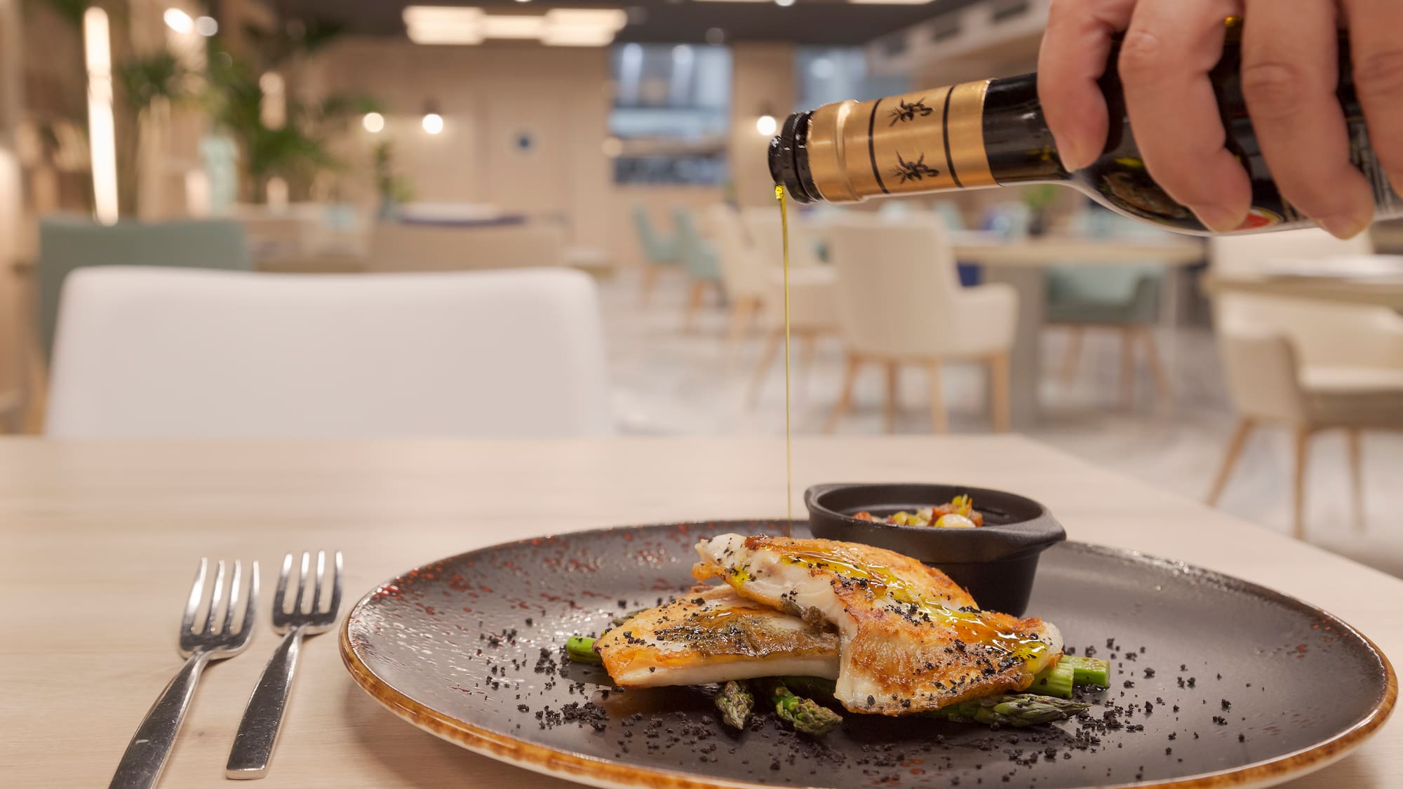 a person pouring a bottle of oil onto a plate of food