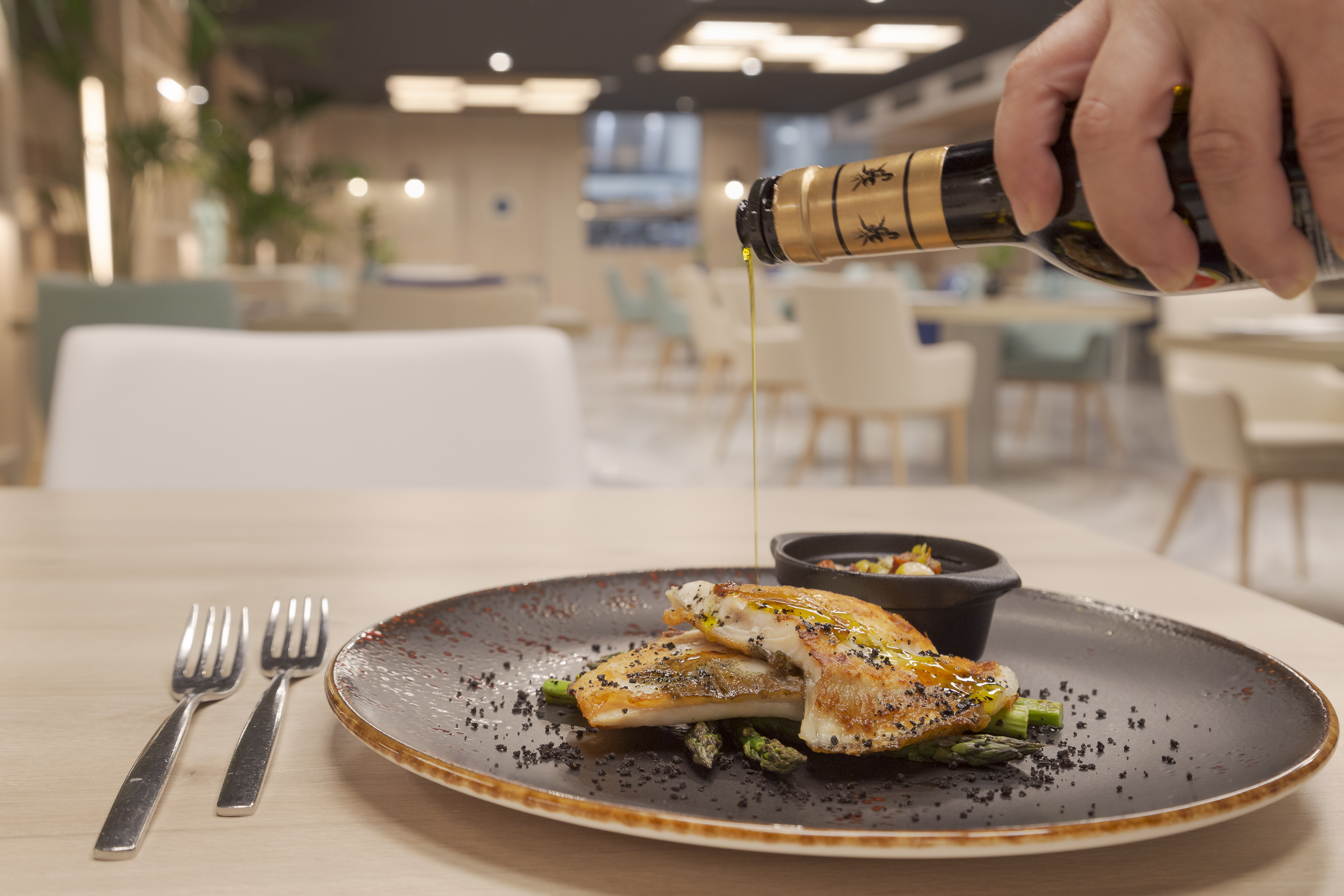 a person pouring a bottle of oil onto a plate of food