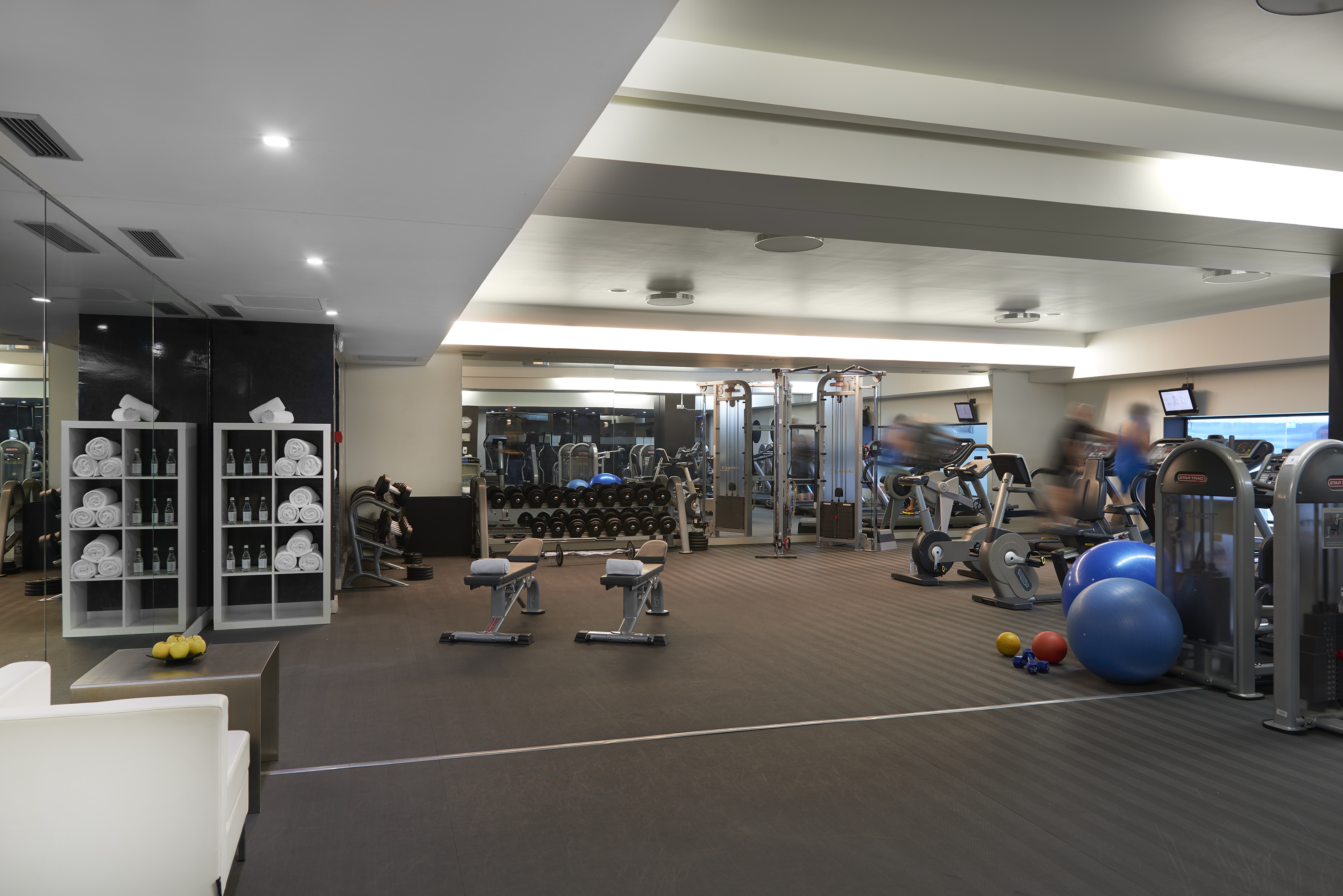 Well-equipped hotel fitness center with cardio machines, weights, and active users.