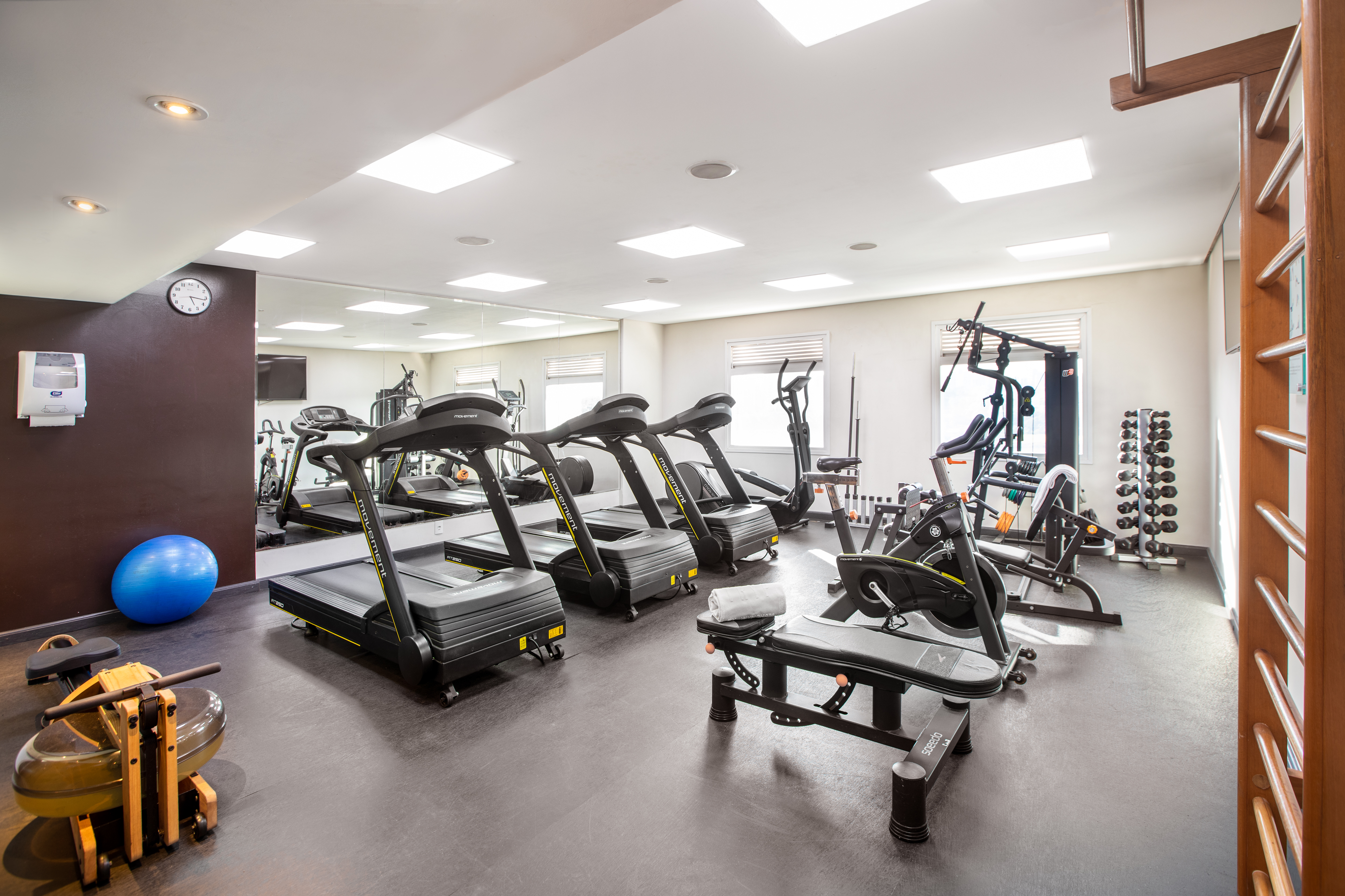 Well-equipped fitness center featuring treadmills, rowing machine, and dumbbells.