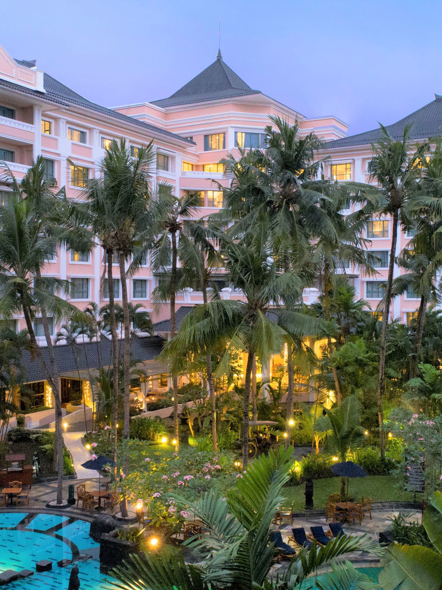 a pool and palm trees in front of a hotel