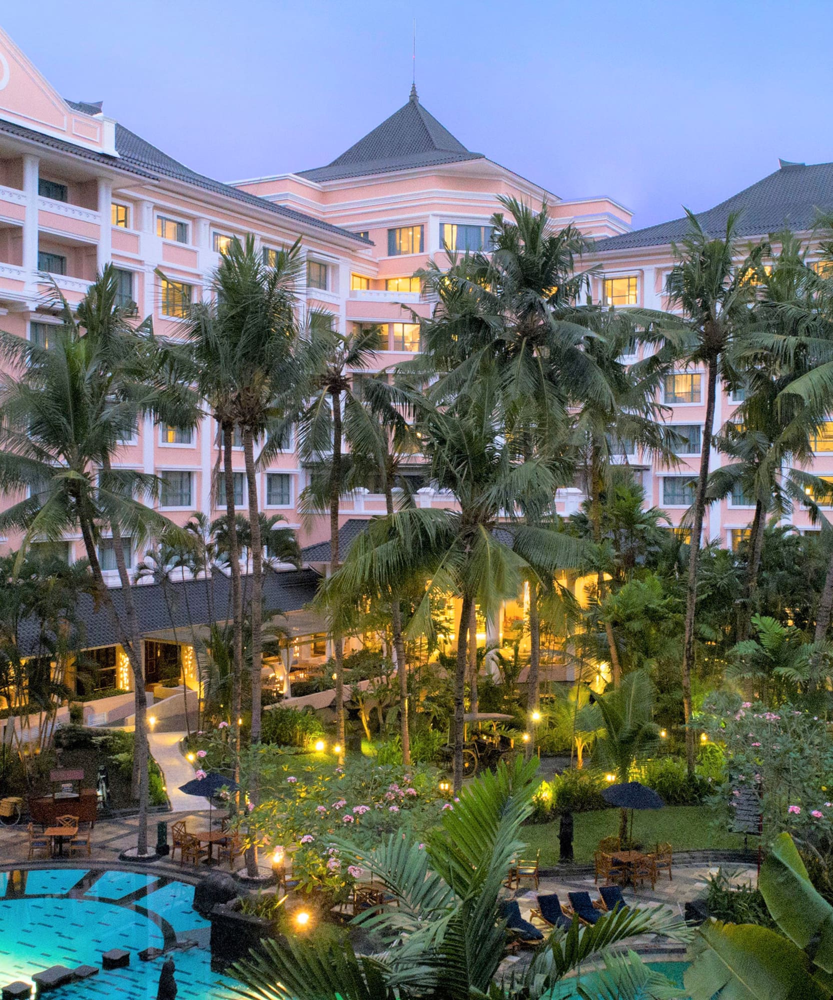 a pool and palm trees in front of a hotel