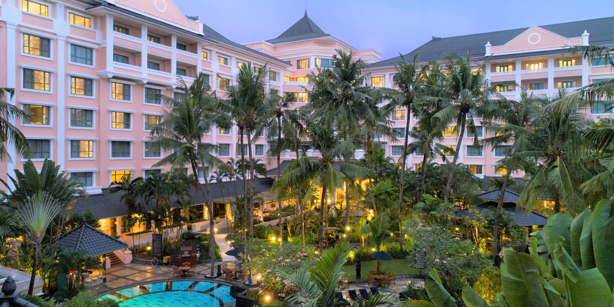 a pool and palm trees in front of a hotel
