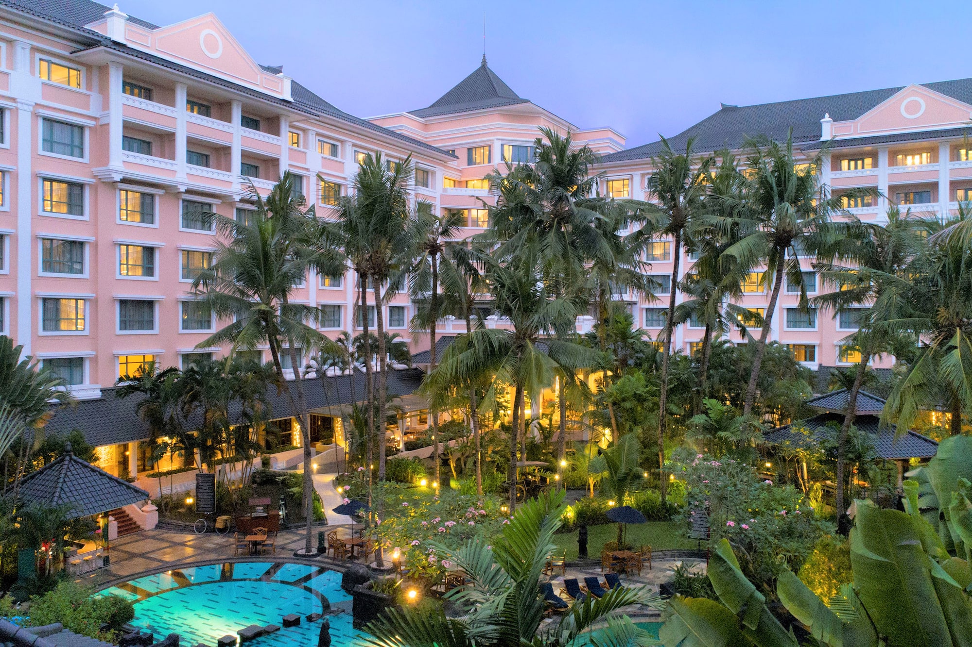 a pool and palm trees in front of a hotel