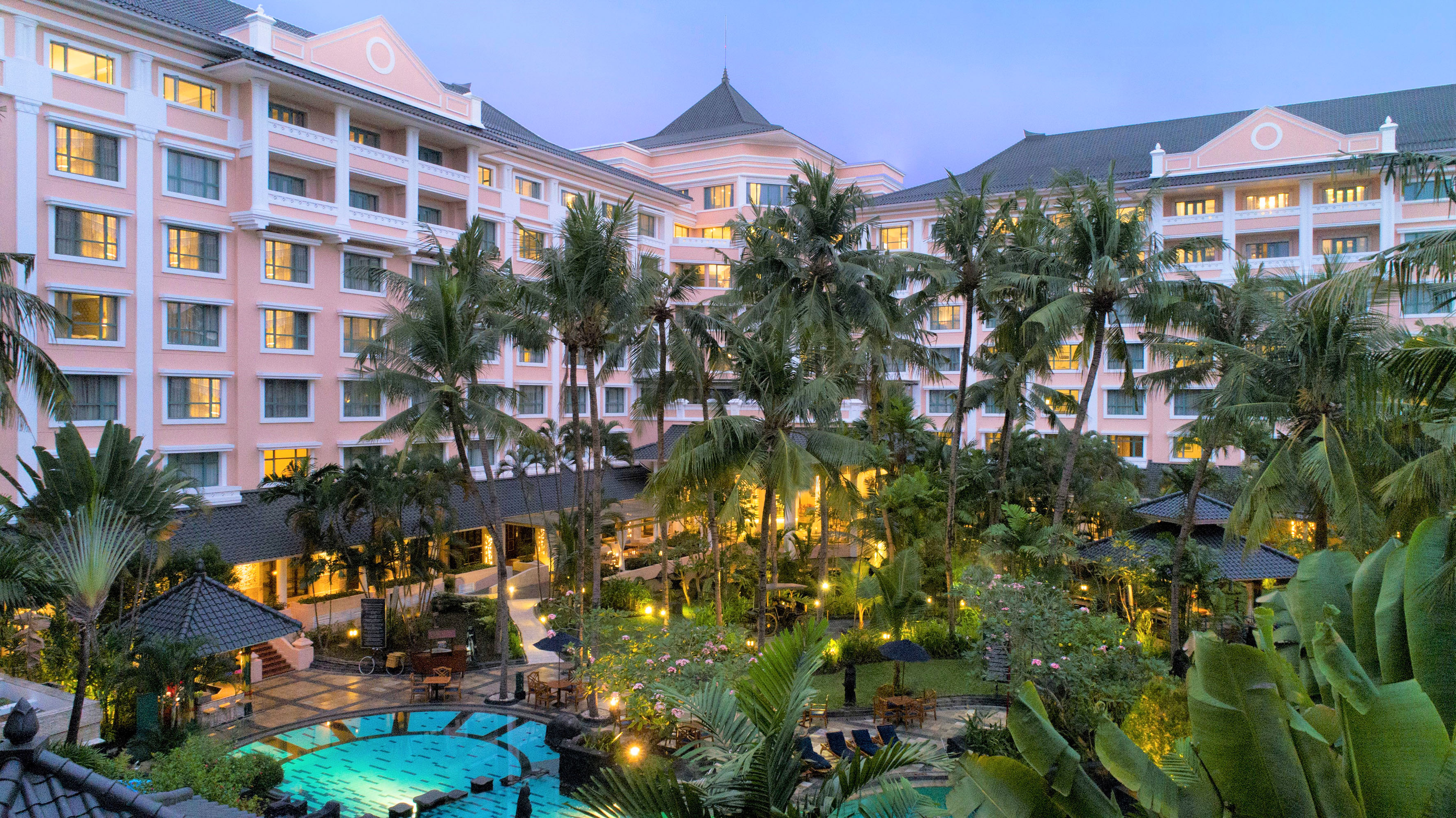 a pool and palm trees in front of a hotel