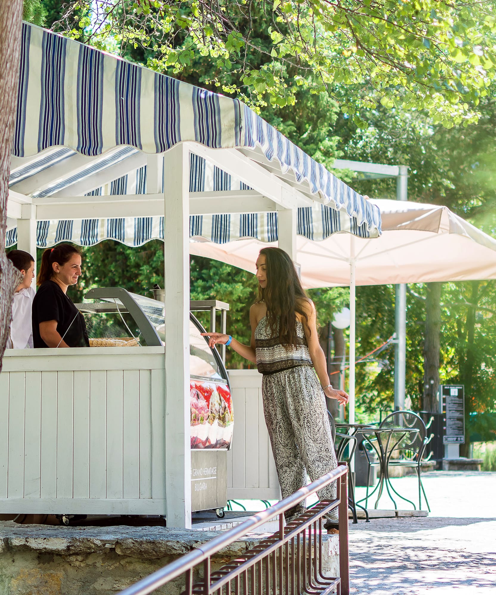 a woman standing in front of a white structure with a striped awning