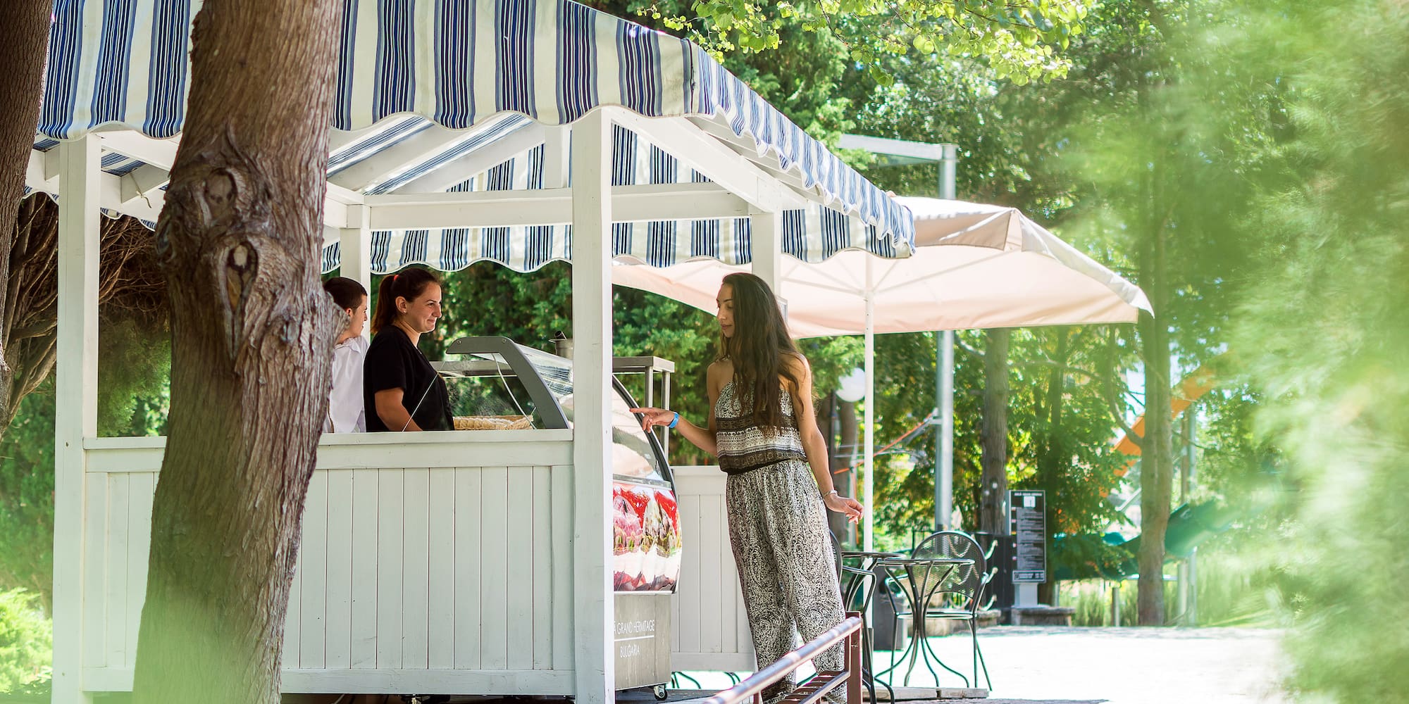 a woman standing in front of a white structure with a striped awning