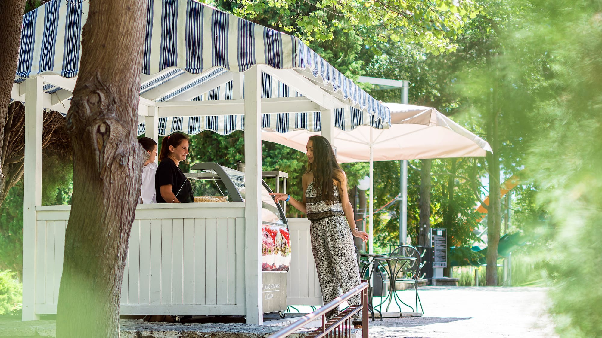 a woman standing in front of a white structure with a striped awning
