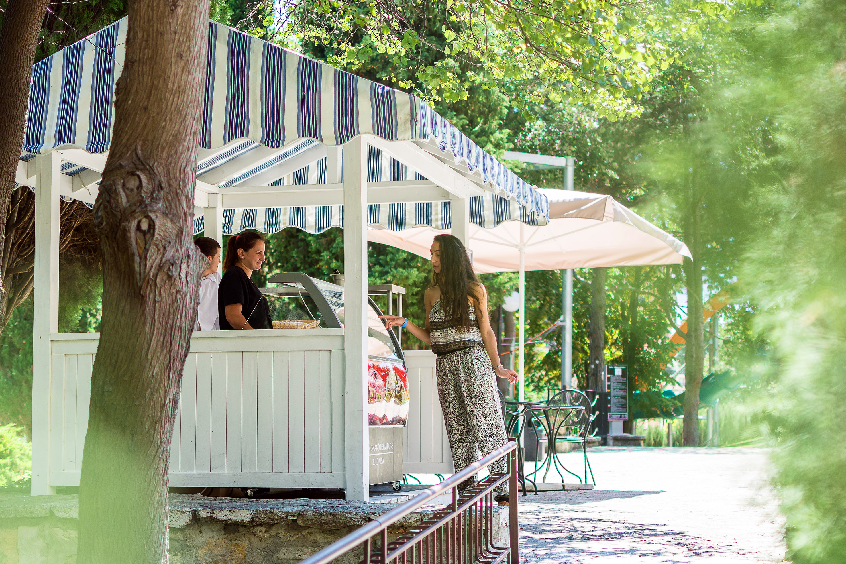 a woman standing in front of a white structure with a striped awning