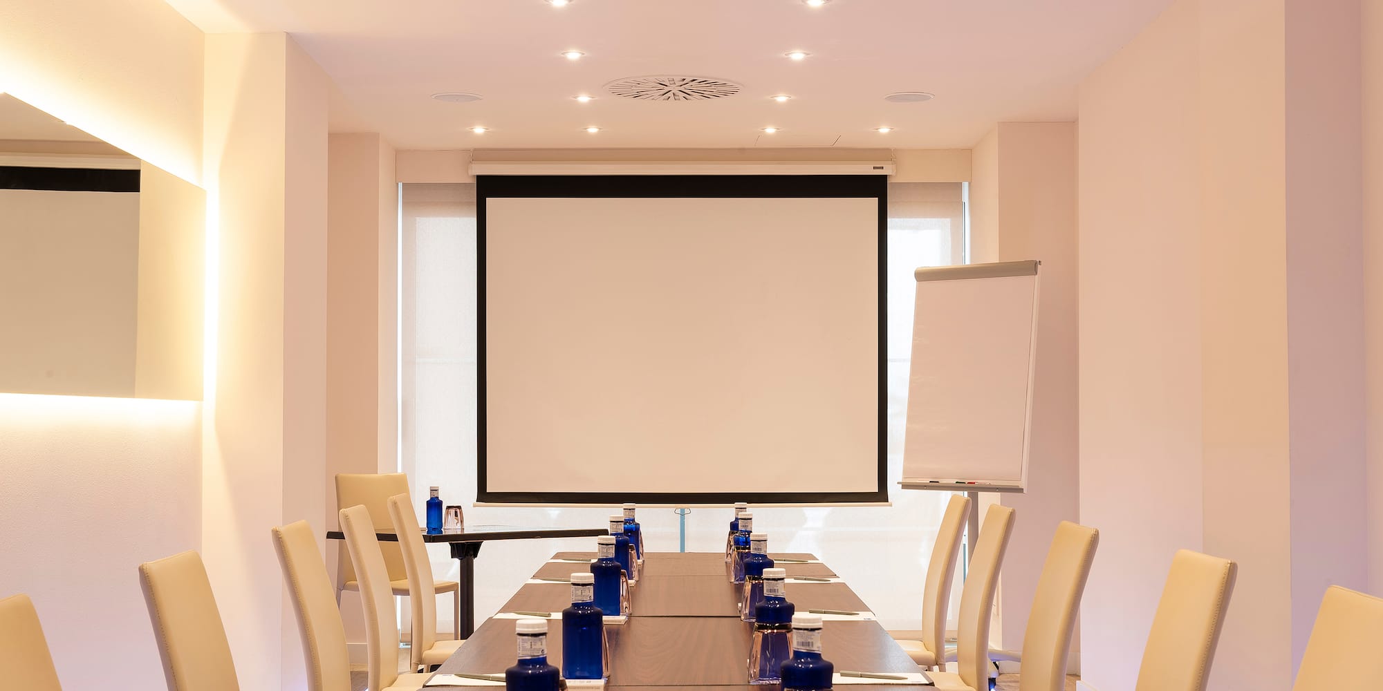 a room with a projection screen and a table with blue objects