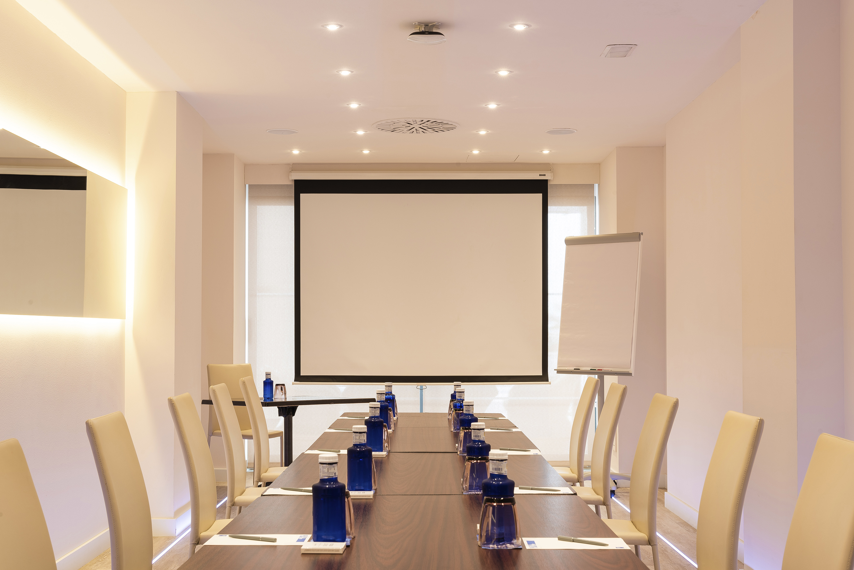 a room with a projection screen and a table with blue objects