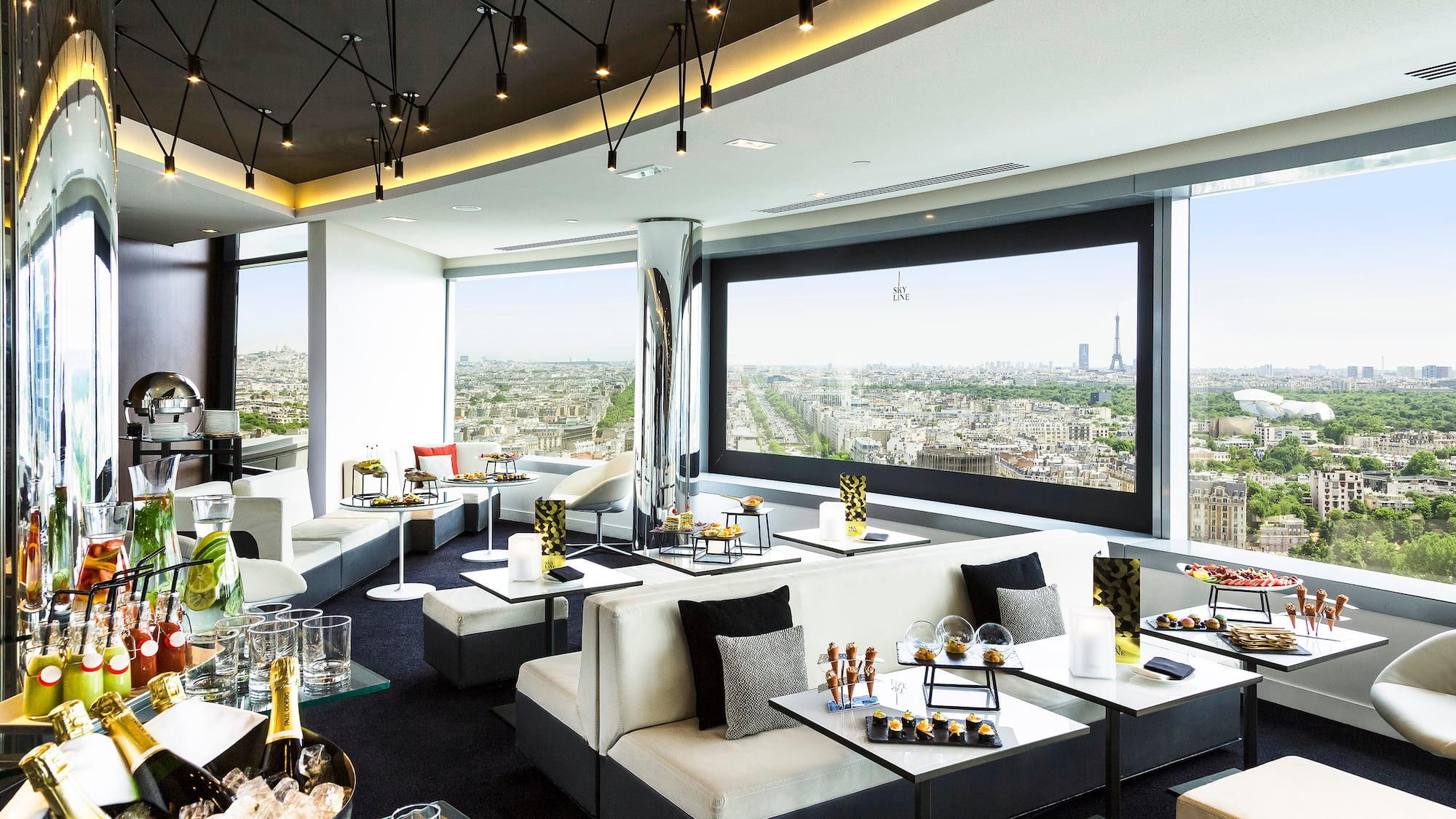 a room with white couches and tables and chairs with a view of a city