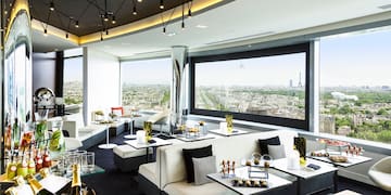 a room with white couches and tables and chairs with a view of a city