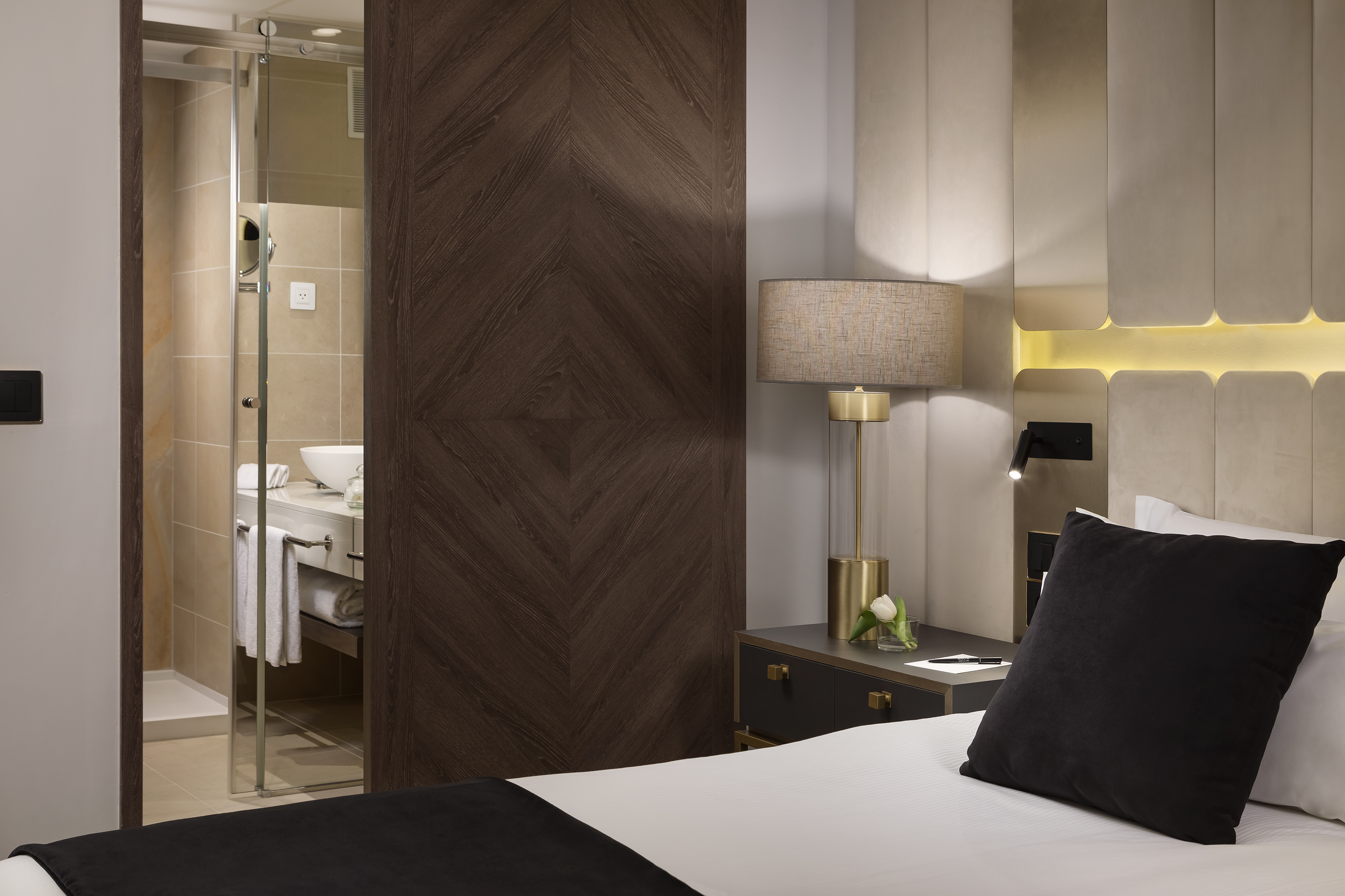 Modern hotel room with bed, illuminated headboard, and adjacent bathroom.