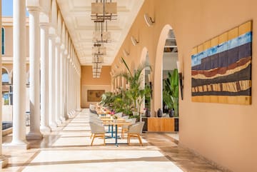 a long hallway with white columns and tables and chairs