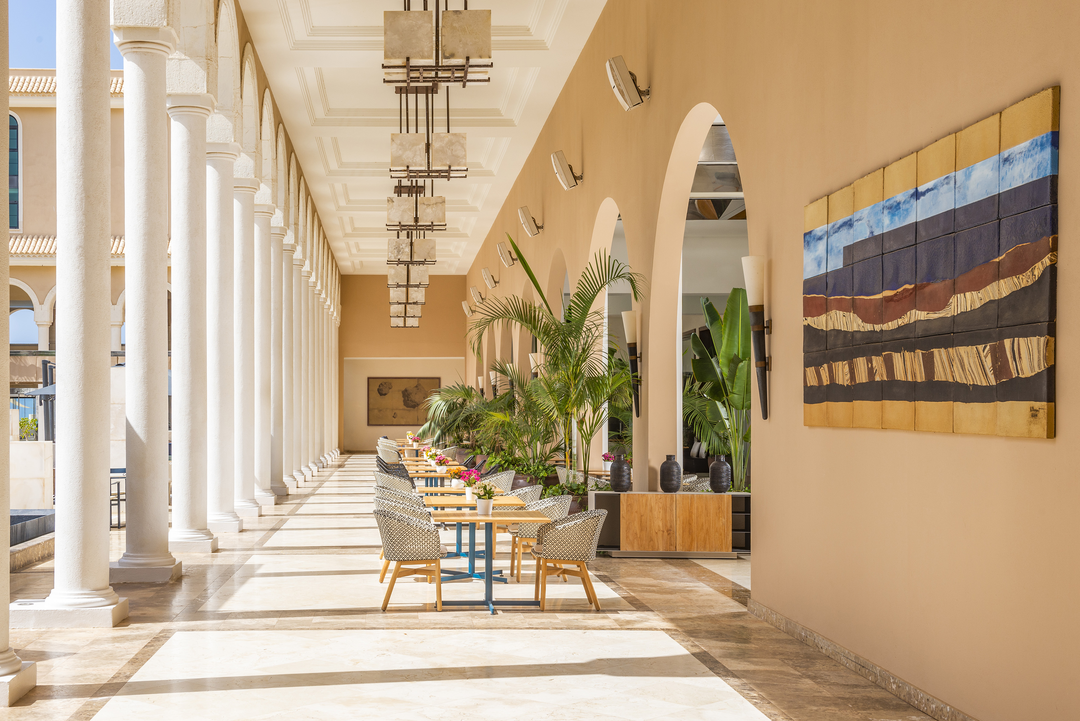 a long hallway with white columns and tables and chairs