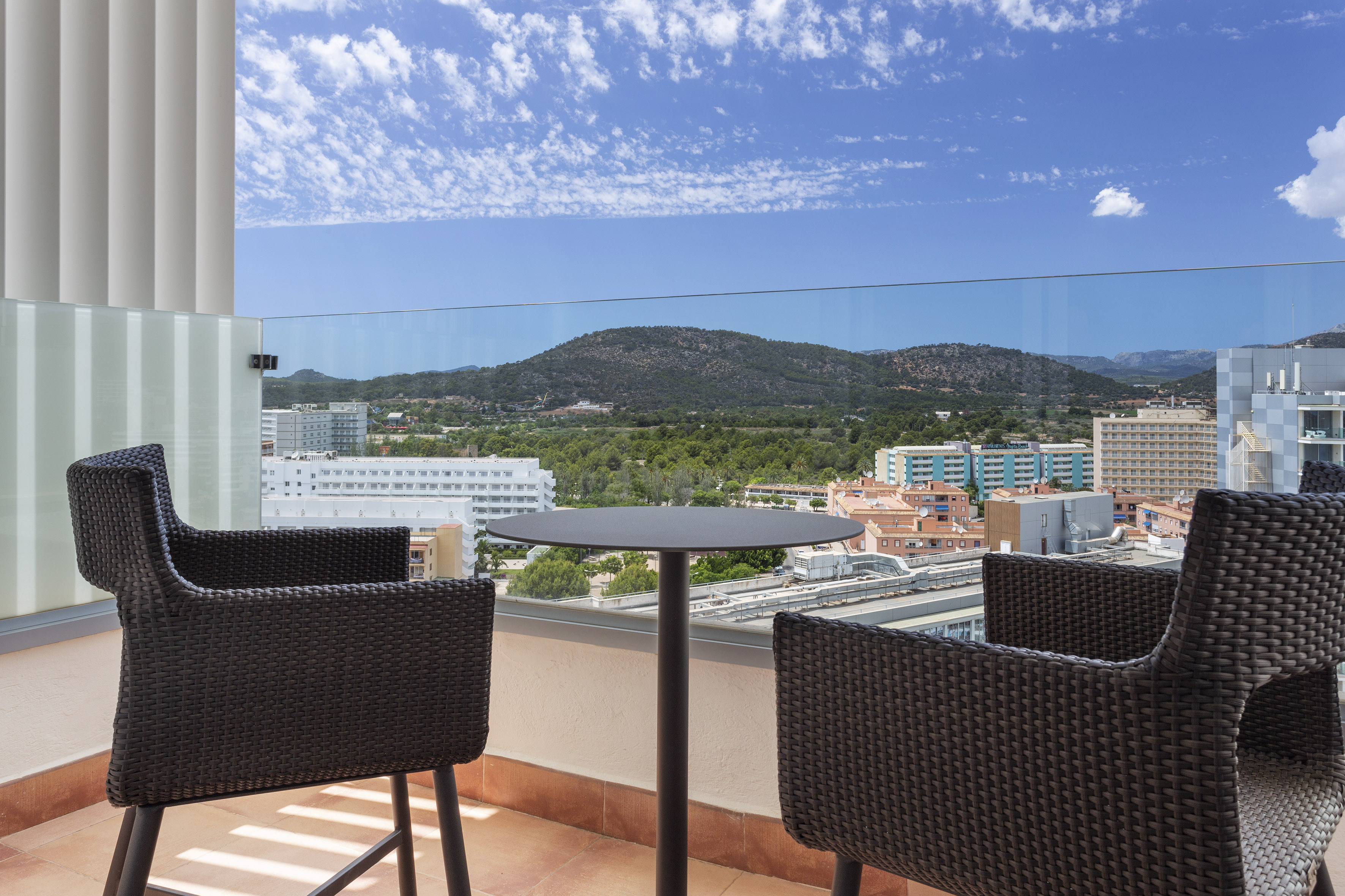 Balcony with outdoor seating, panoramic city and mountain view.