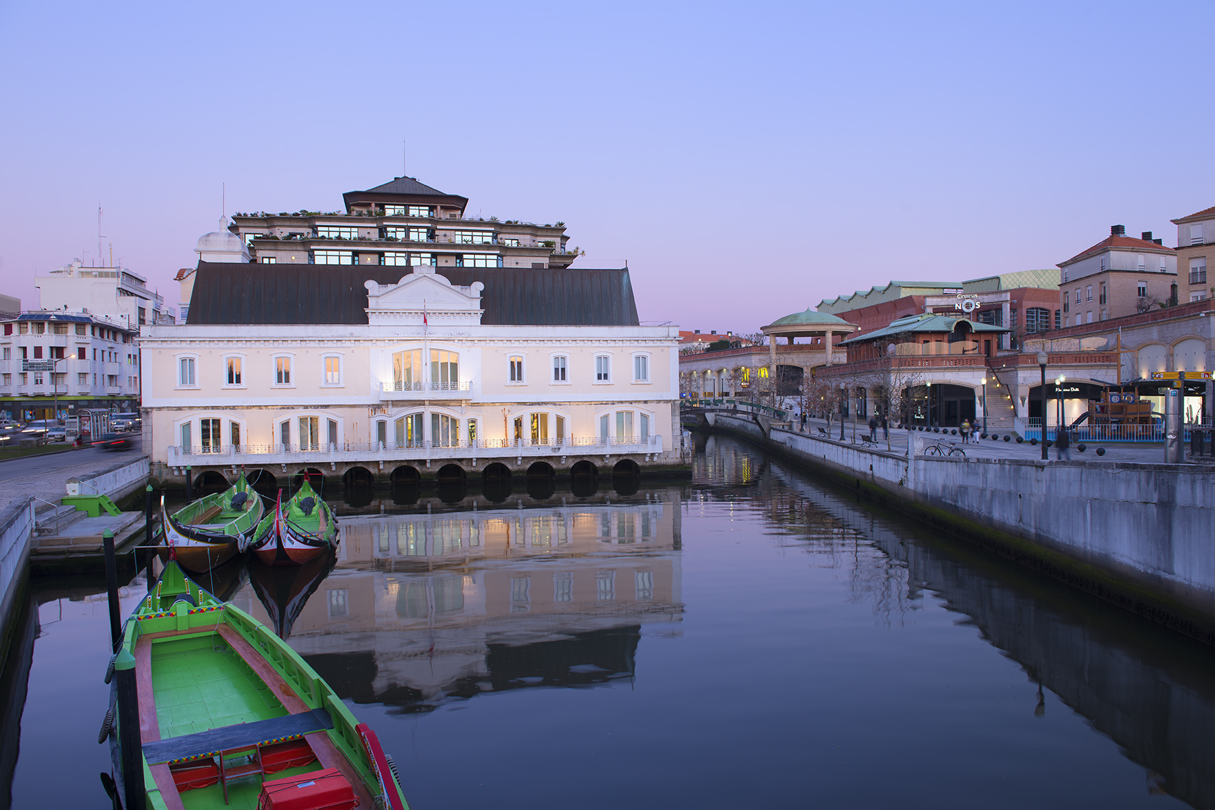 Aveiro canal with moliceiro boats, waterfront buildings reflecting at dusk.