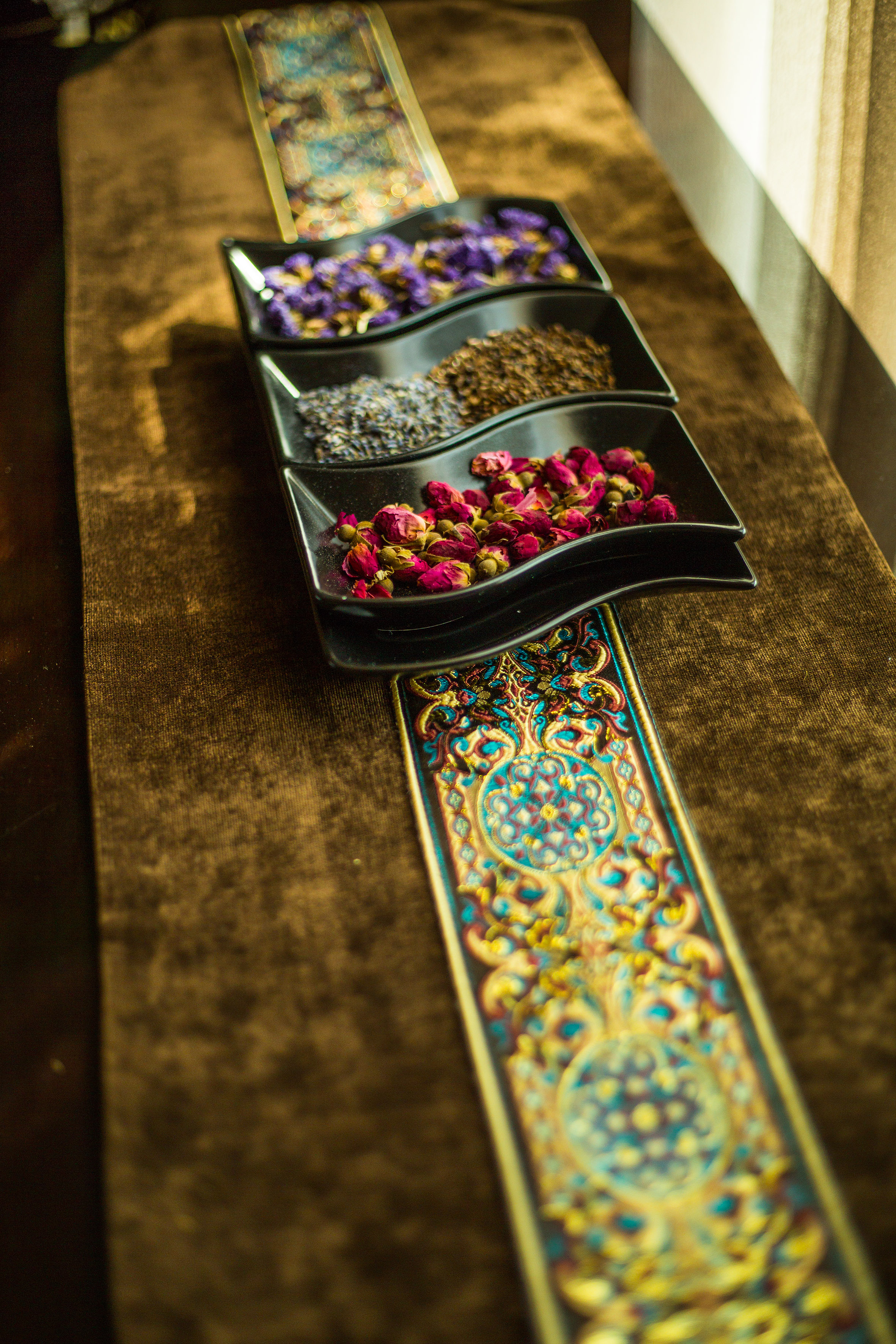 Dried butterfly pea, lavender, rosebuds, and tea leaves in black dish.