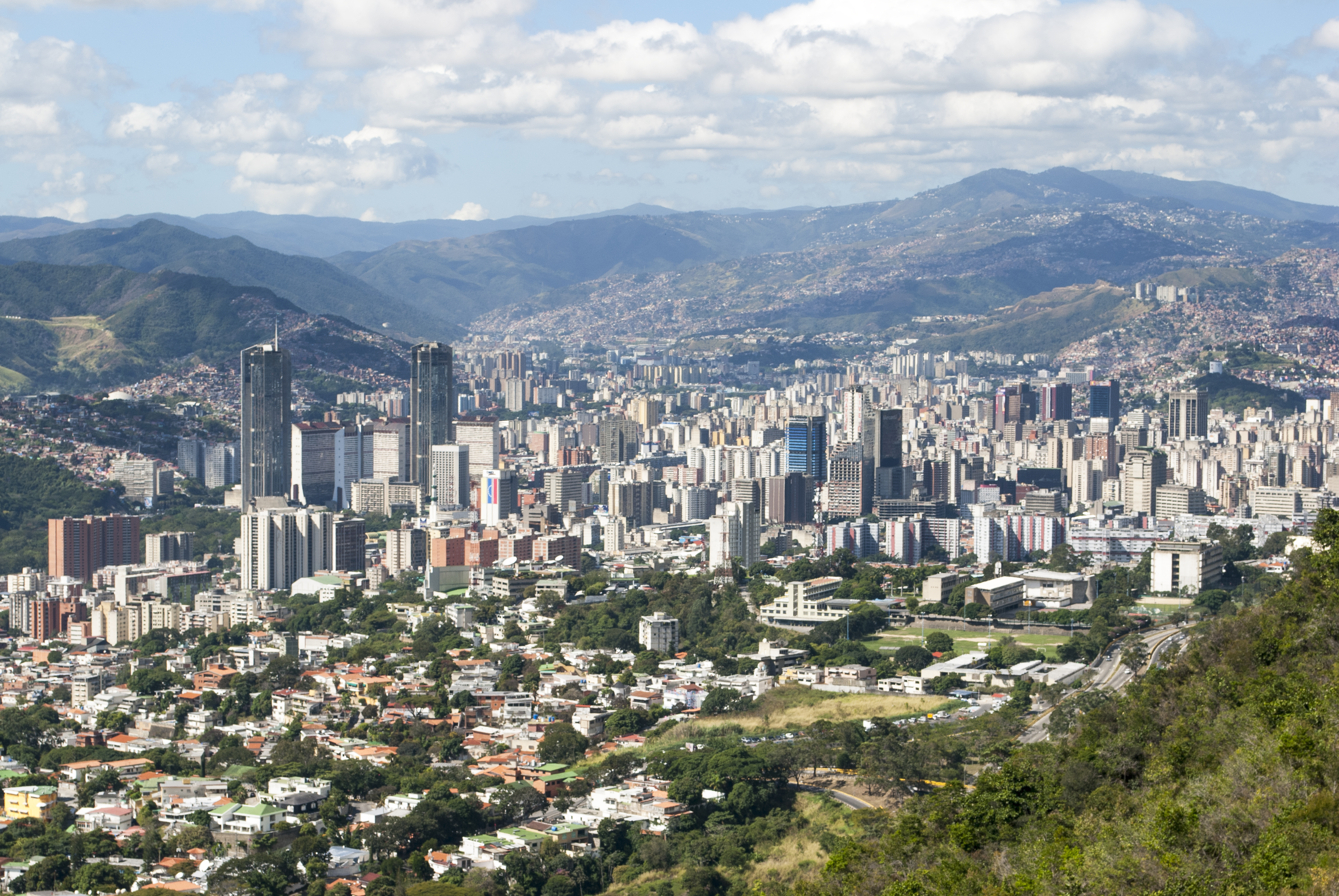 Dense urban skyline nestled within a mountain valley on a cloudy day.