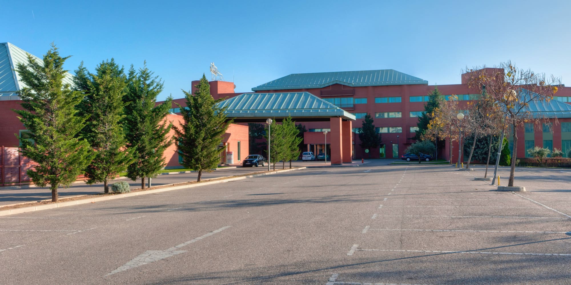 a parking lot with trees and a building