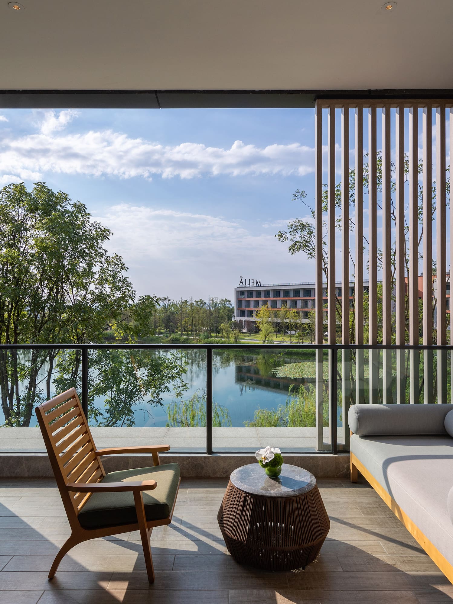 Modern hotel balcony with outdoor furniture and a serene lake view.