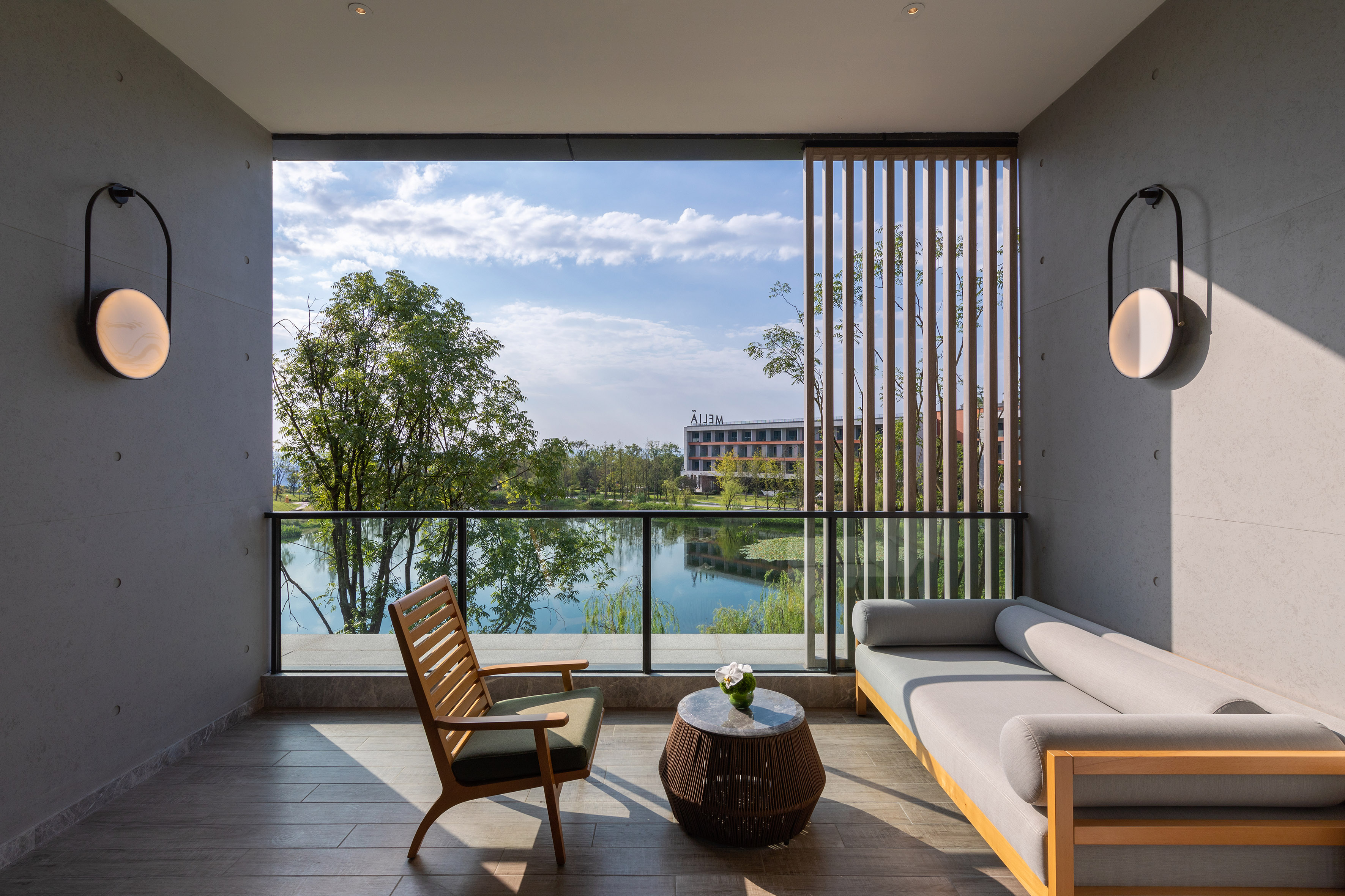 Modern balcony with lake view, outdoor lounge furniture, and resort building.
