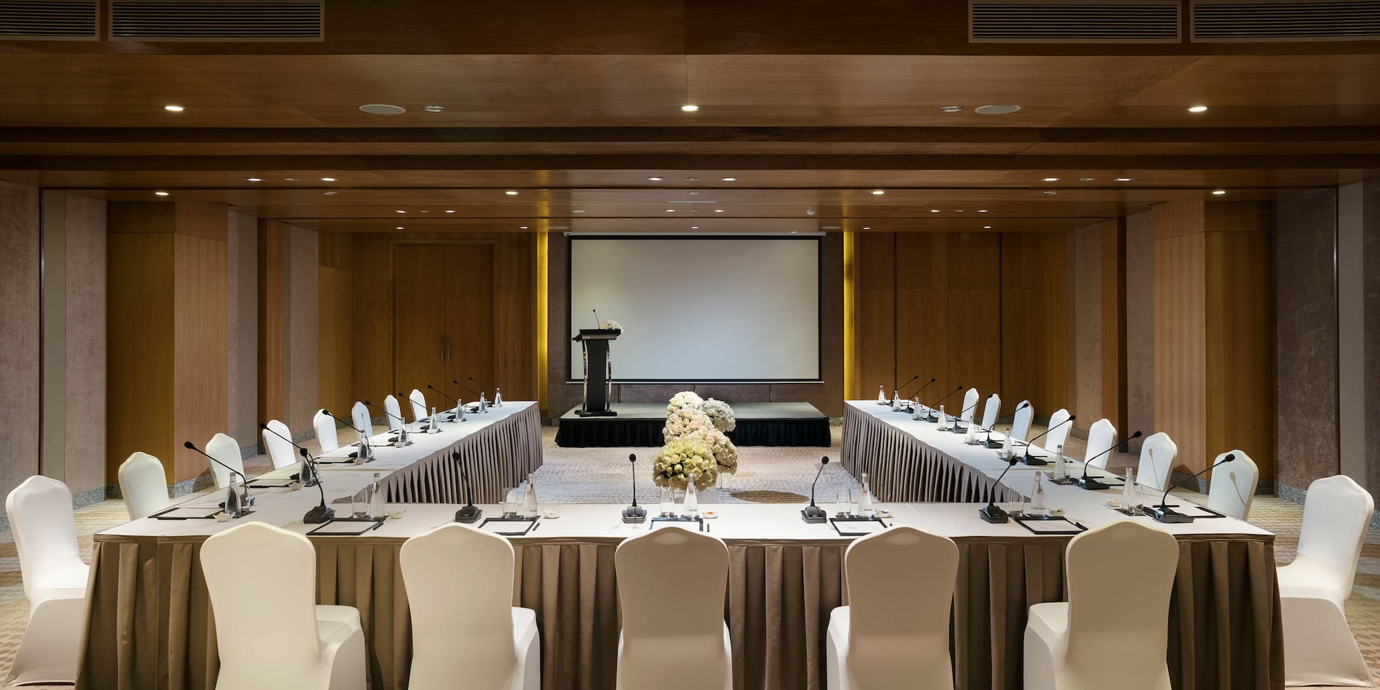 a room with a large table with chairs and a projector screen